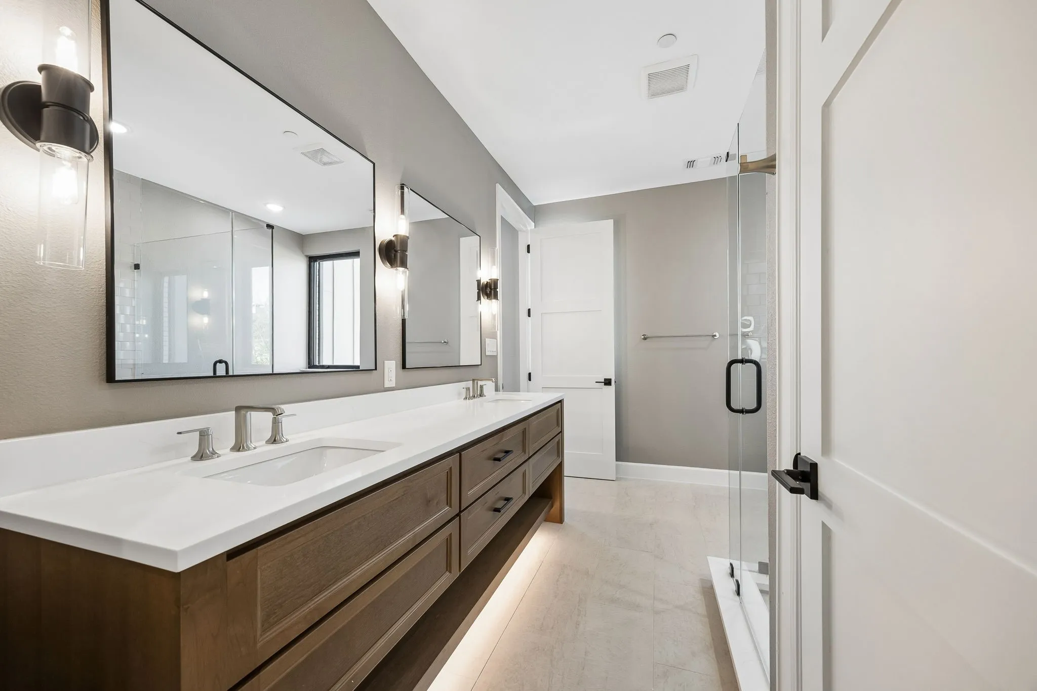 Double vanity featuring a white countertop, undermount sinks, and wood-finish cabinetry with drawer storage