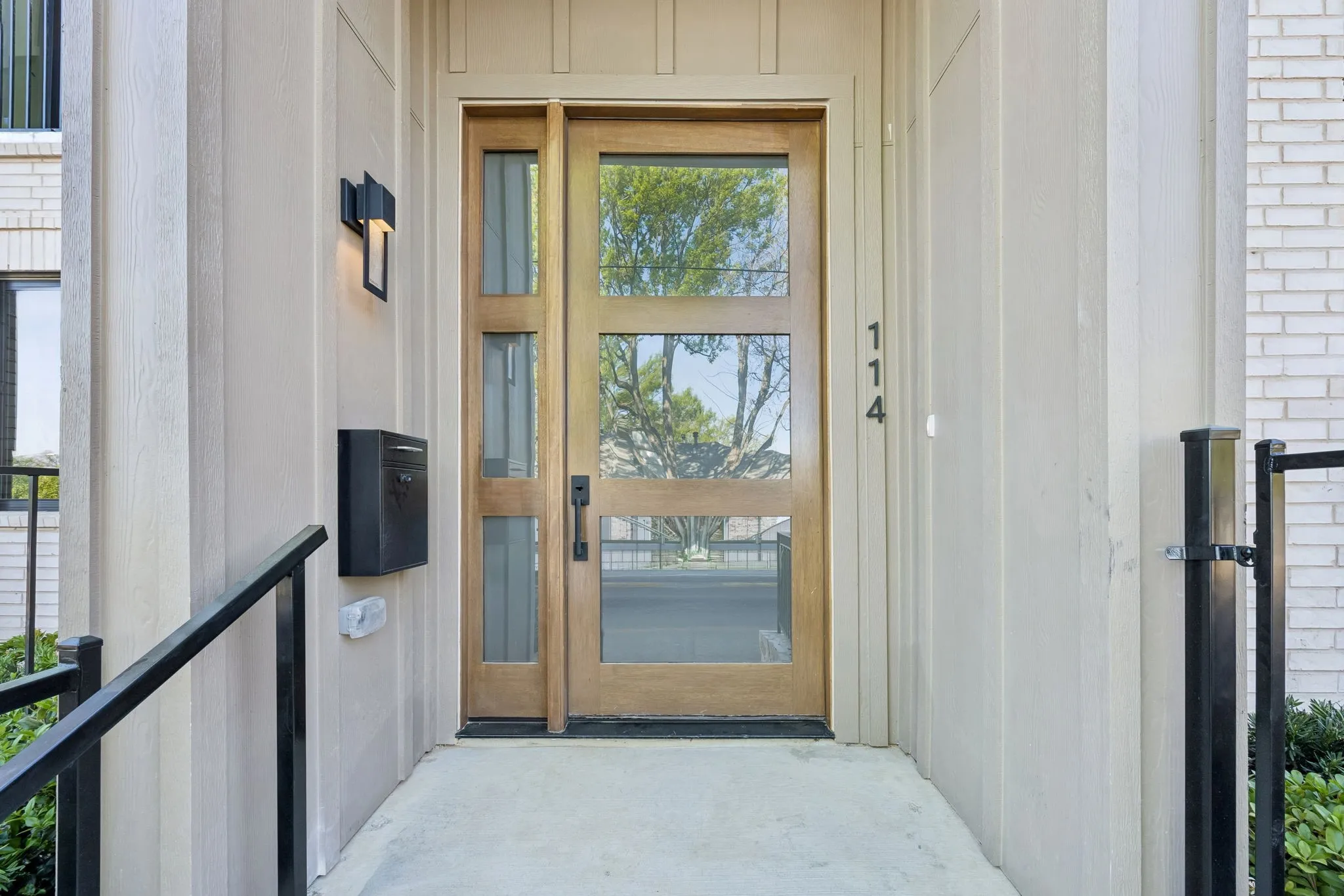 Modern entry door with multiple glass lites and side lite, complemented by a contemporary exterior sconce and mounted mailbox