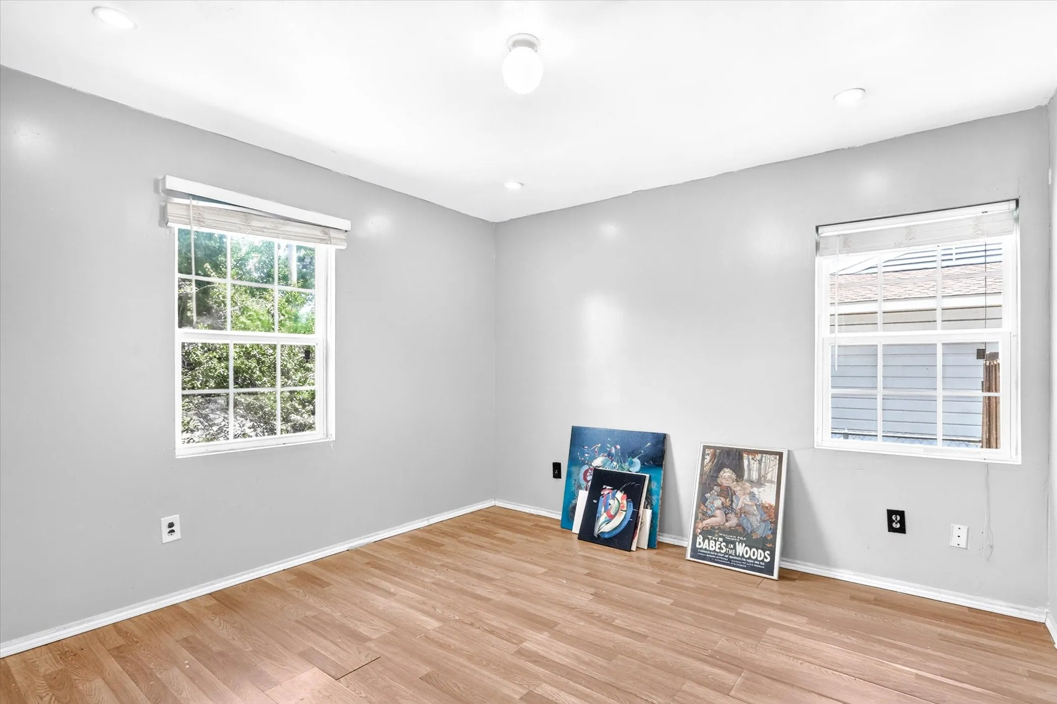 Bedroom featuring two large windows, white trim, and light gray walls