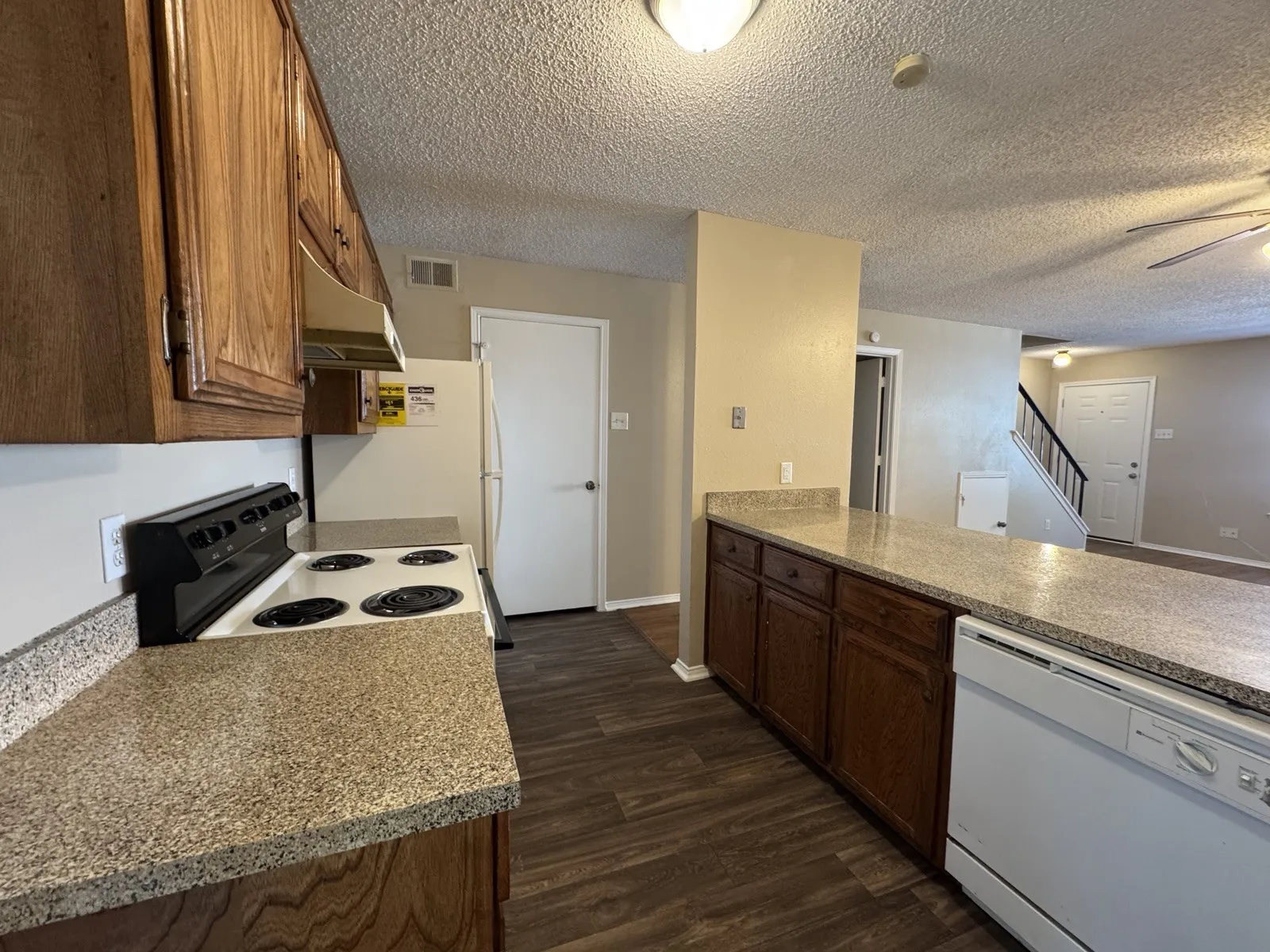 Kitchen featuring wood-finish cabinetry, speckled countertops, and a built-in dishwasher