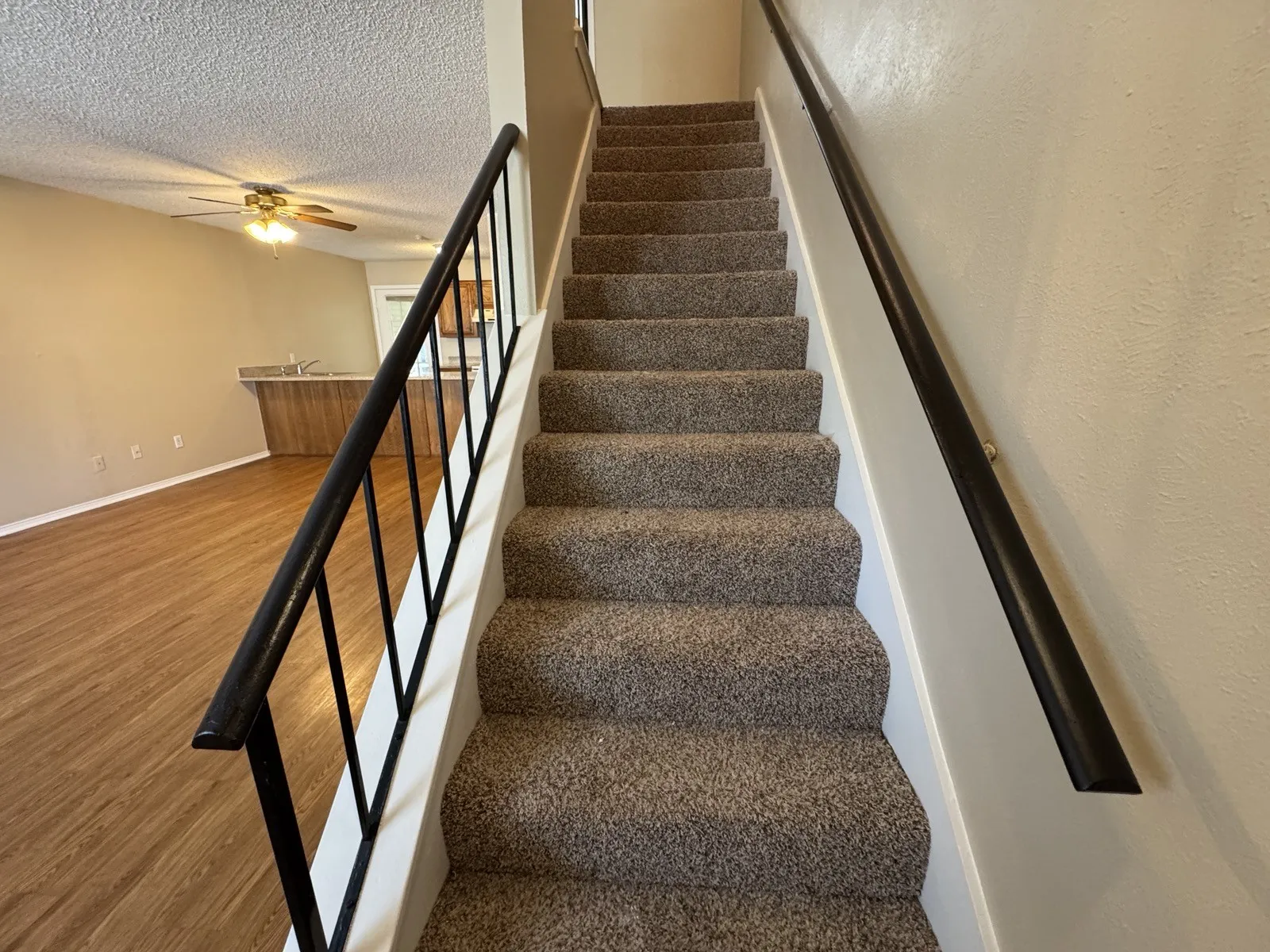 Carpeted staircase with dark metal handrails