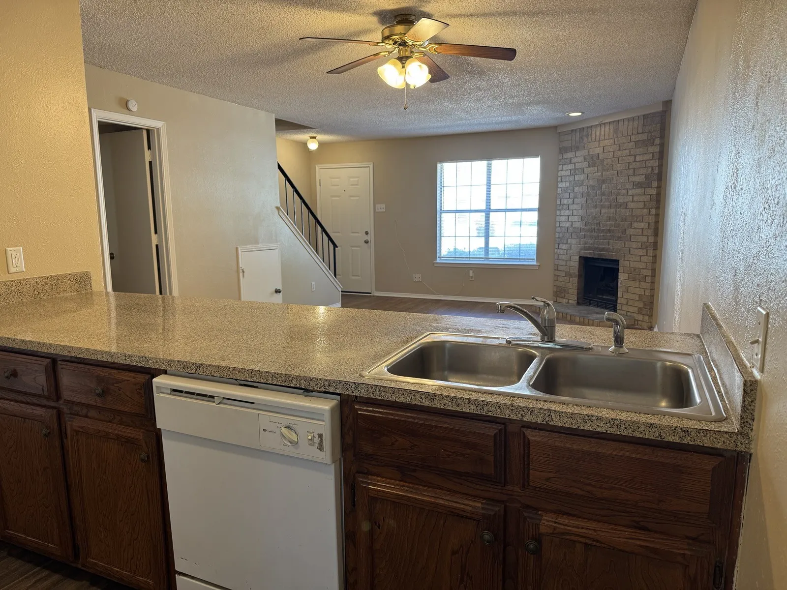 Kitchen counter with a dual-basin stainless steel sink, integrated dishwasher, and wood-finish cabinetry