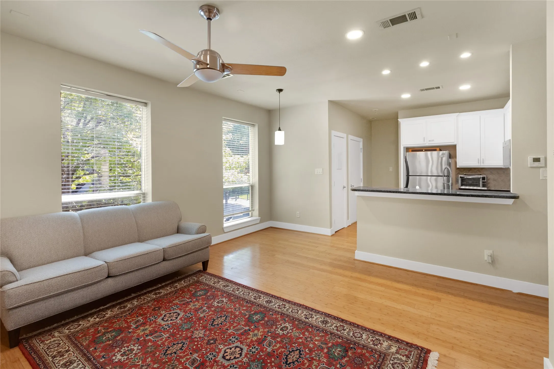 Open-concept living space featuring wood-finish flooring, recessed lighting, and a modern ceiling fan