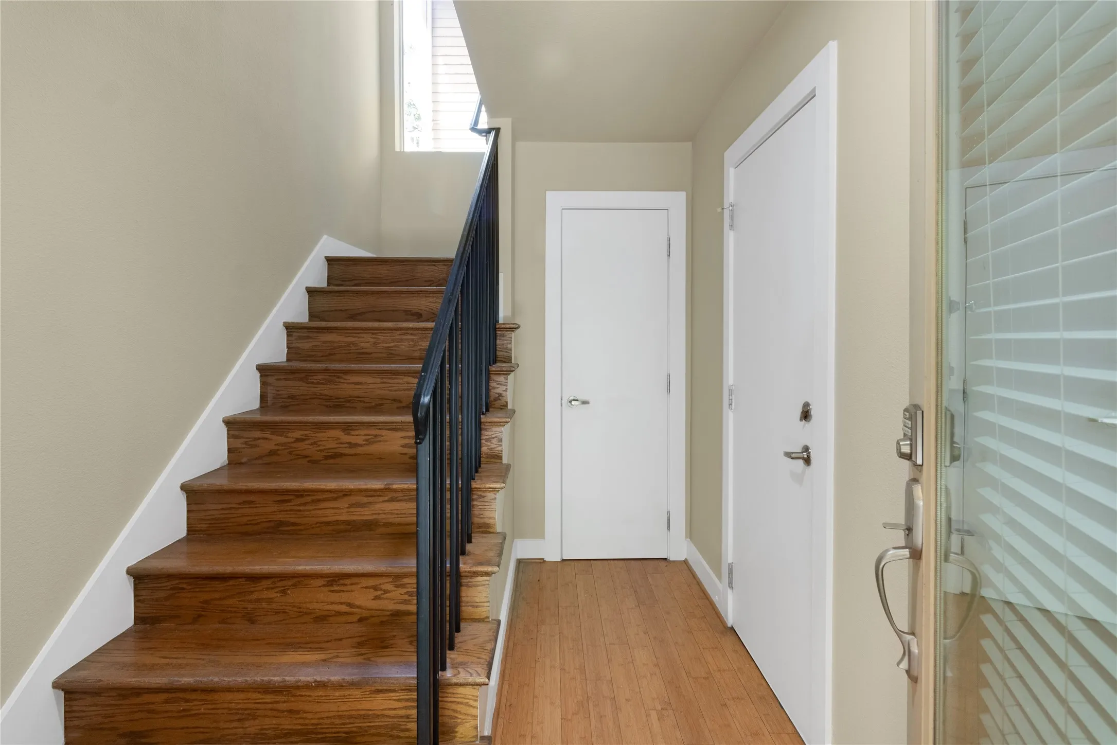 Hardwood staircase featuring a black metal handrail and white risers