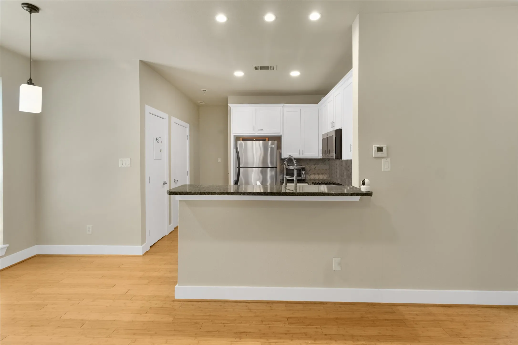 Open concept living area featuring wood-finish flooring, recessed lighting, and a kitchen with white cabinetry