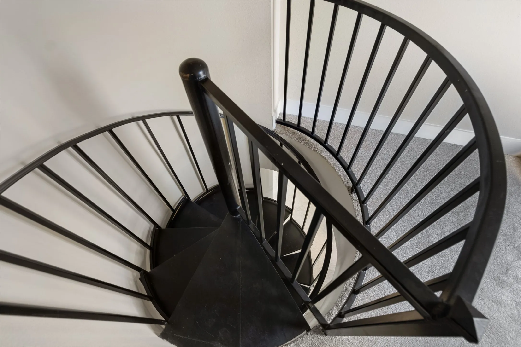Black spiral staircase with dark wood-finish treads and contemporary black metal balusters