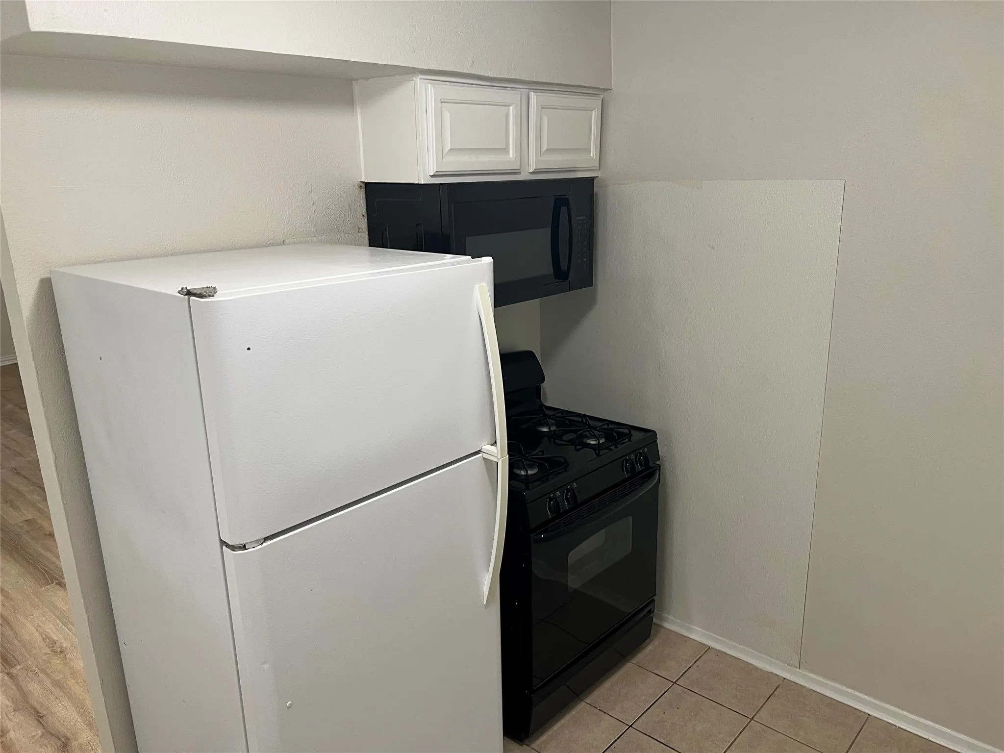 Kitchen area featuring a white top-freezer refrigerator, a black gas range, and an over-the-range microwave