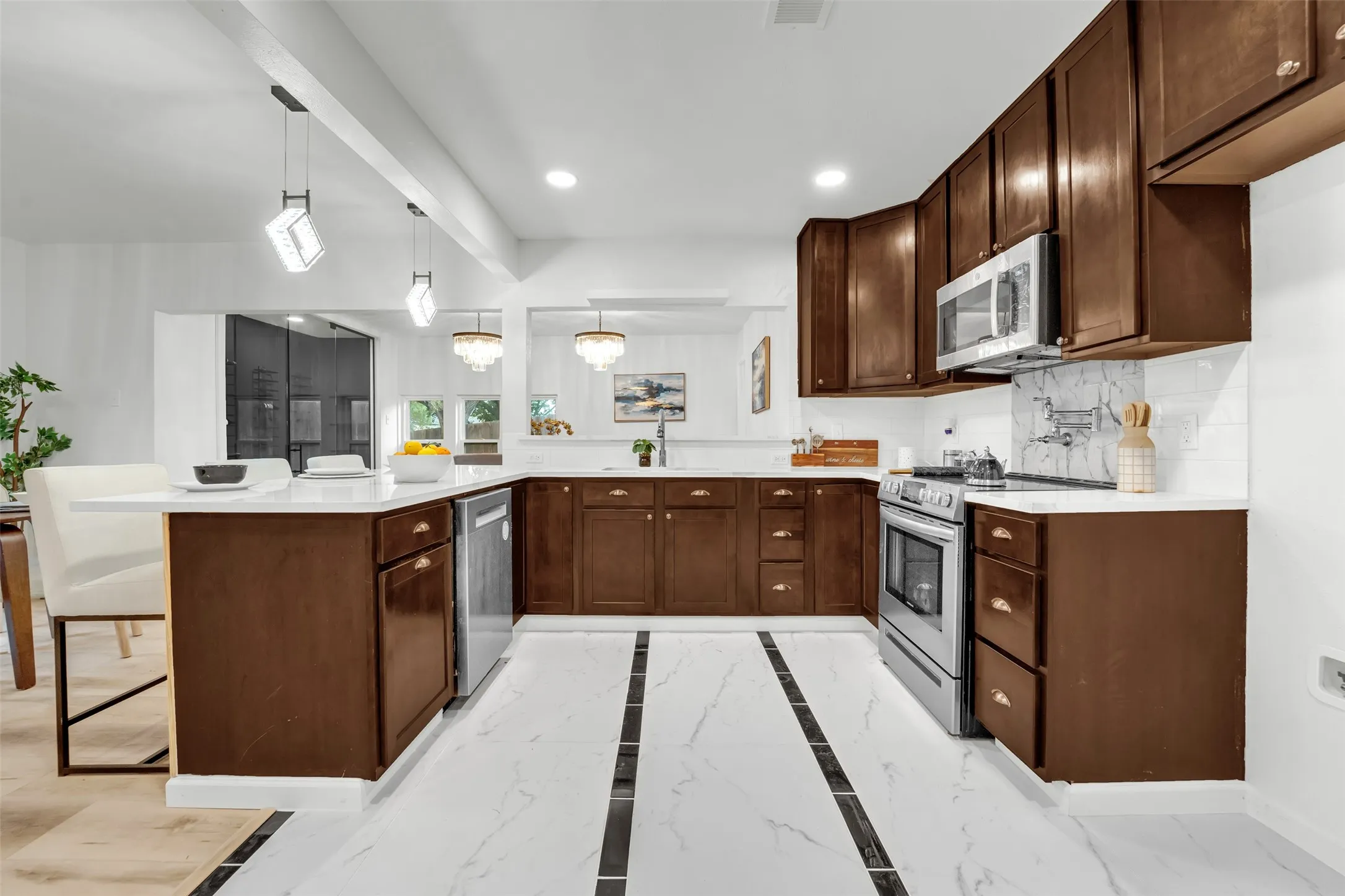 U-shaped kitchen featuring dark wood cabinetry, white countertops, and stainless steel appliances