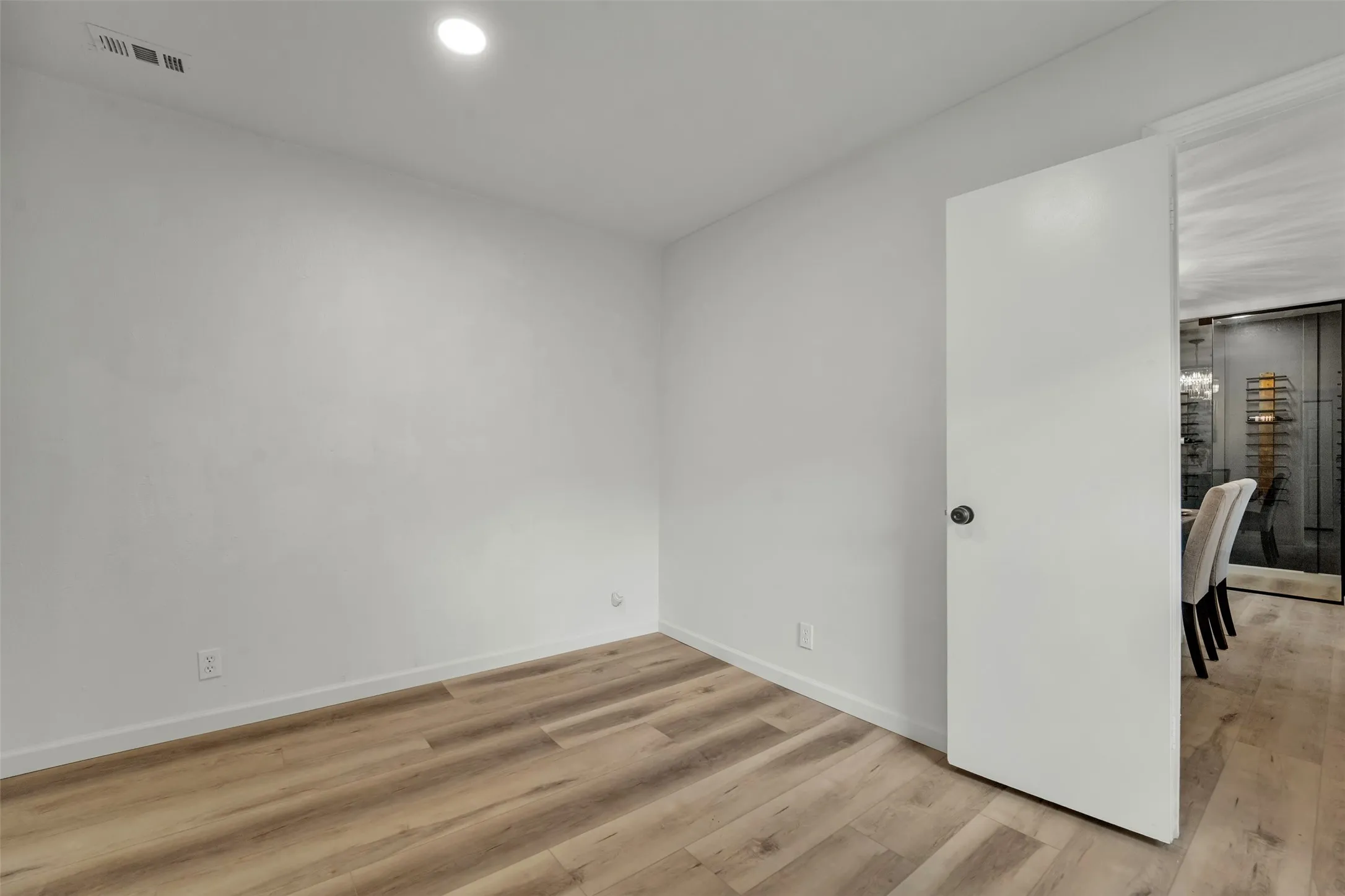Room with light wood-finish flooring, white baseboards, and neutral wall paint