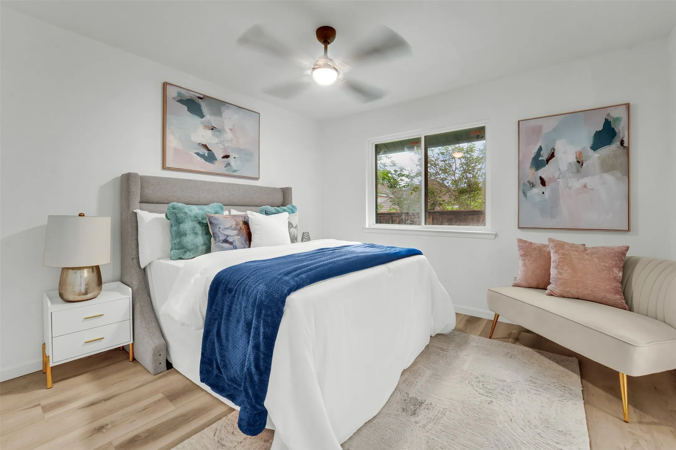 Bright bedroom featuring a recessed window, wood-finish flooring, a ceiling fan with integrated lighting, and white walls