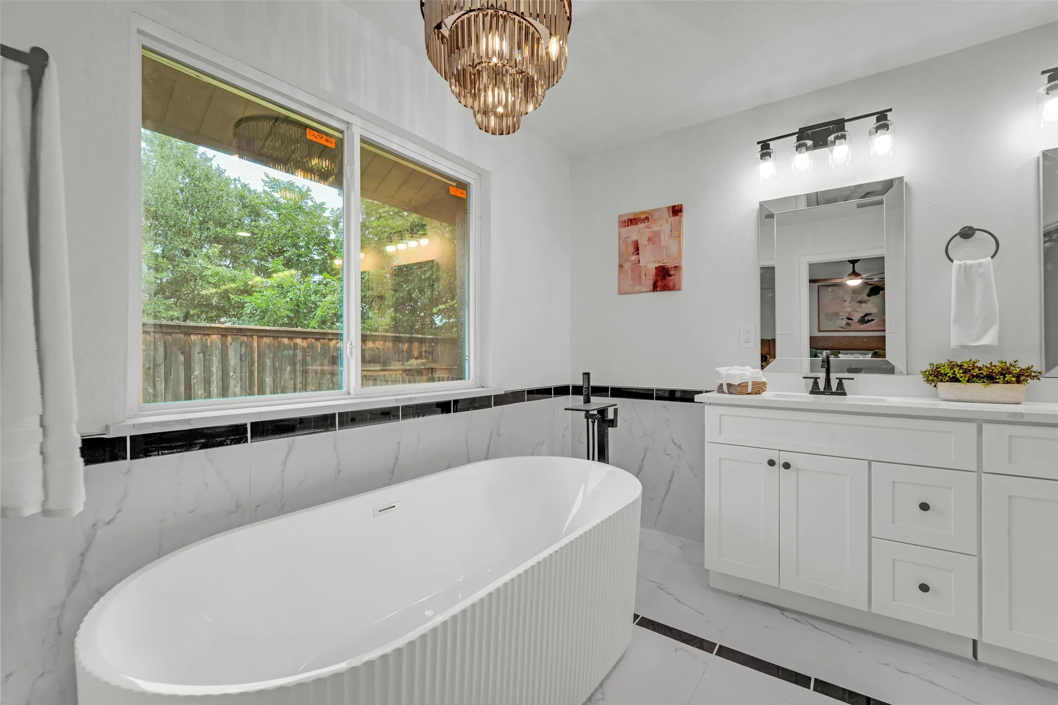 Freestanding soaking tub with a floor-mounted matte black faucet, set against a backdrop of white and black marble-look wall tiling
