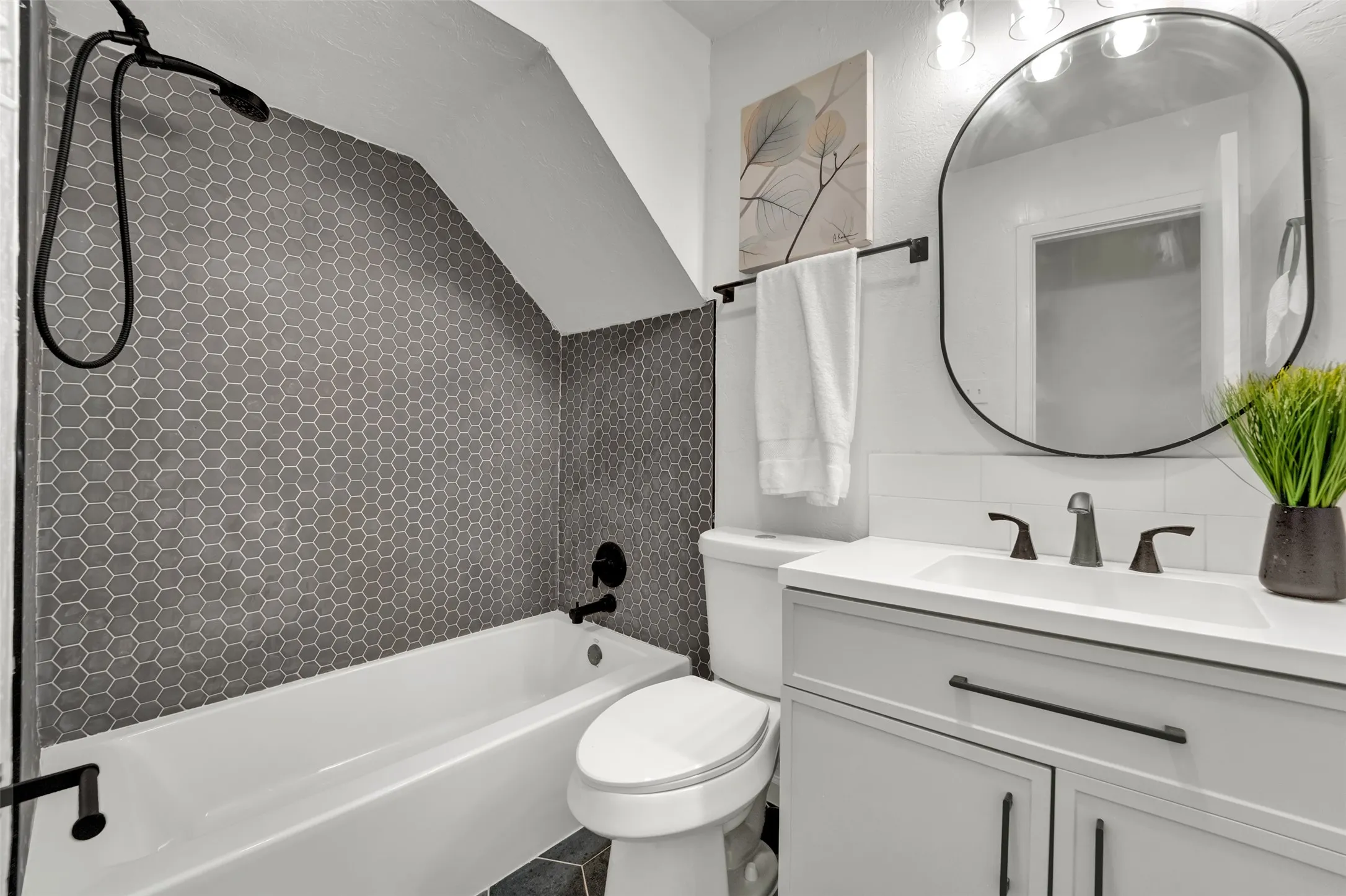 Bathroom featuring a white vanity with a rectangular sink, matte black fixtures, and a modern oval mirror