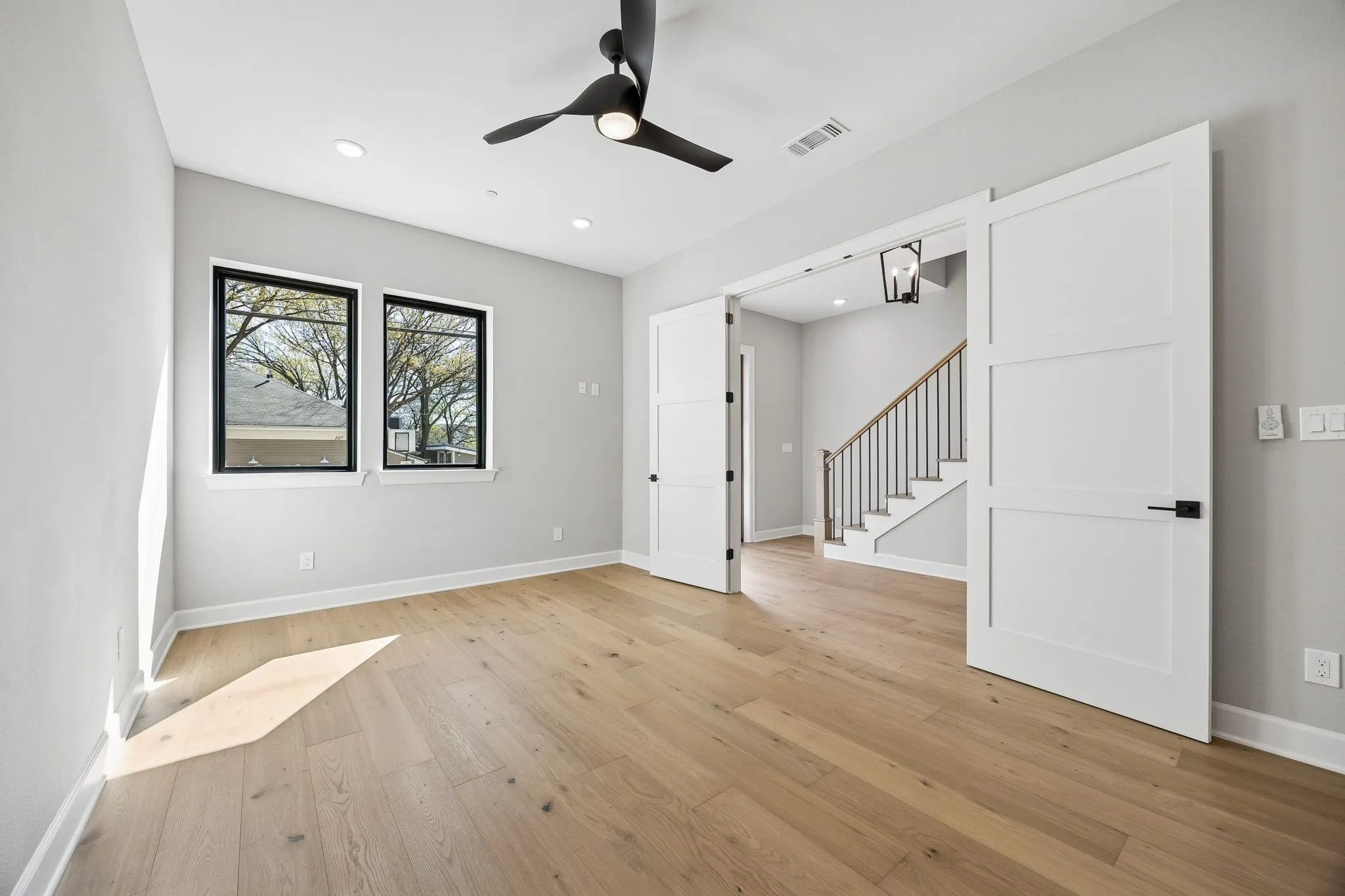 Spacious interior room featuring light wood-finish flooring and two black-framed windows