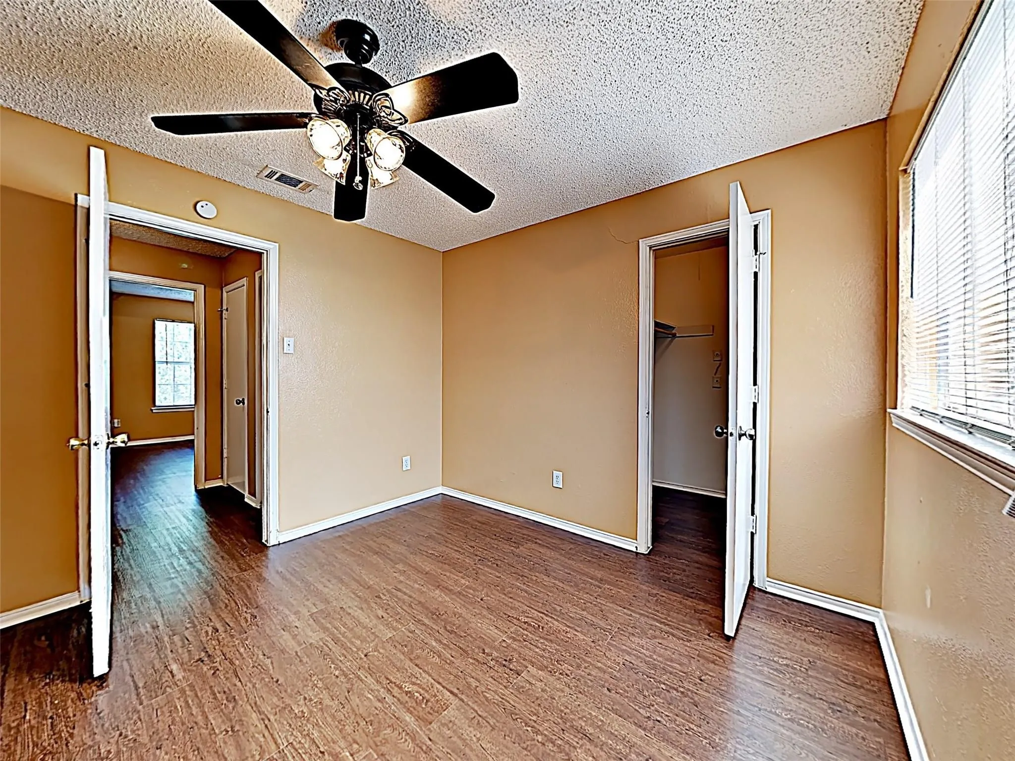 Room featuring wood-finish flooring, a ceiling fan with integrated lighting, and neutral wall tones