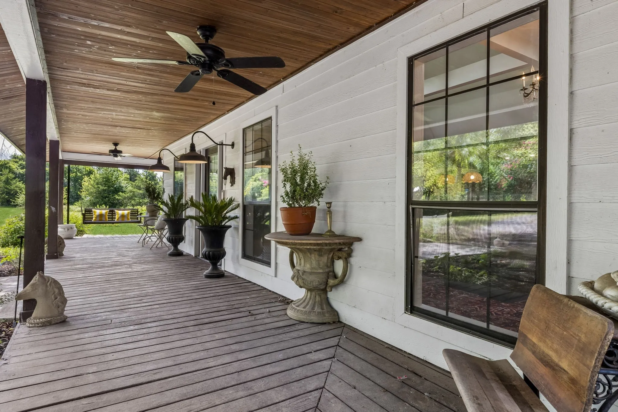 Spacious and inviting wraparound porch with wood ceiling.
