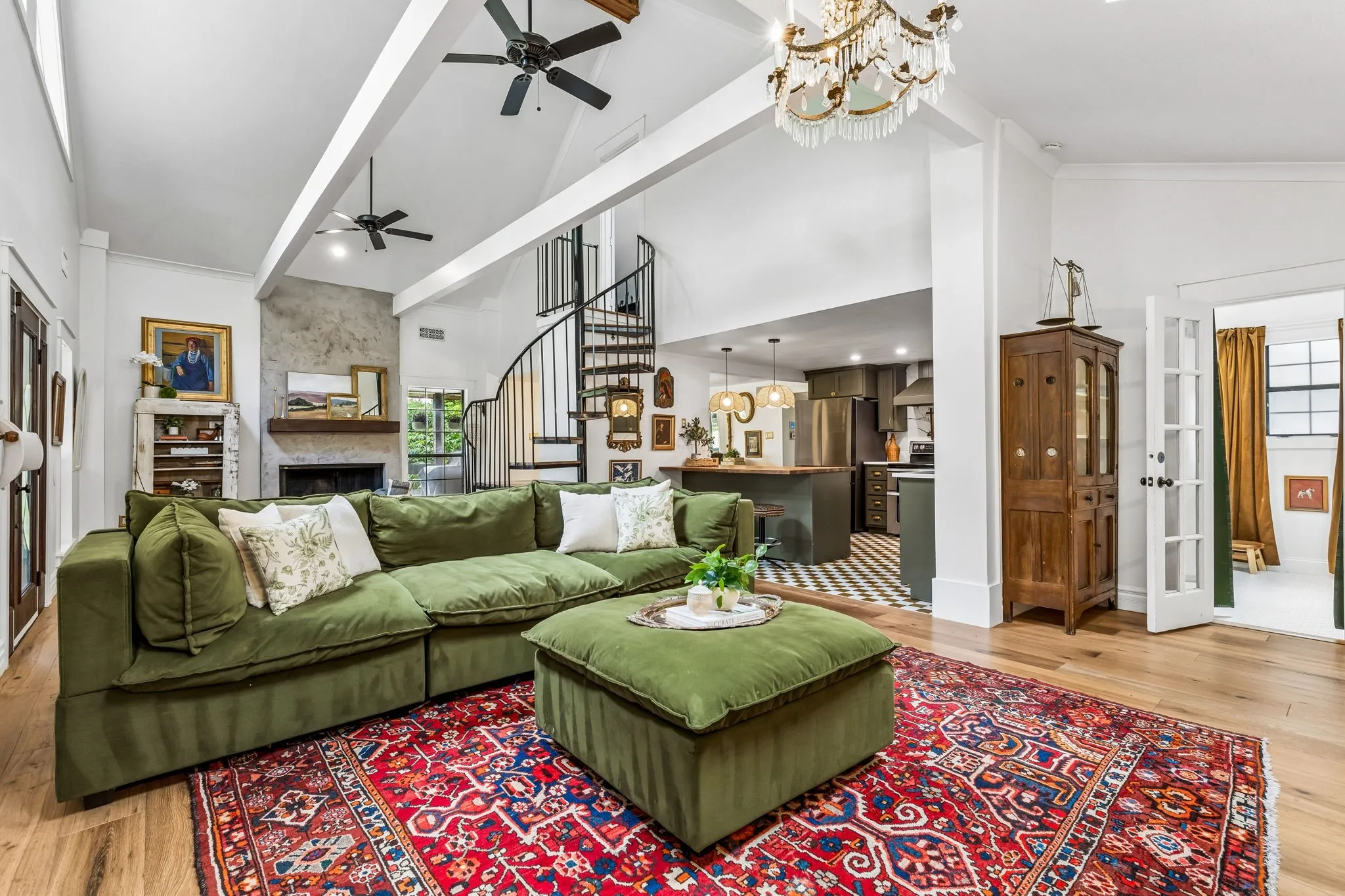 Vaulted ceiling with exposed beams, dramatic spiral staircase, and ethereal lighting from the skylights