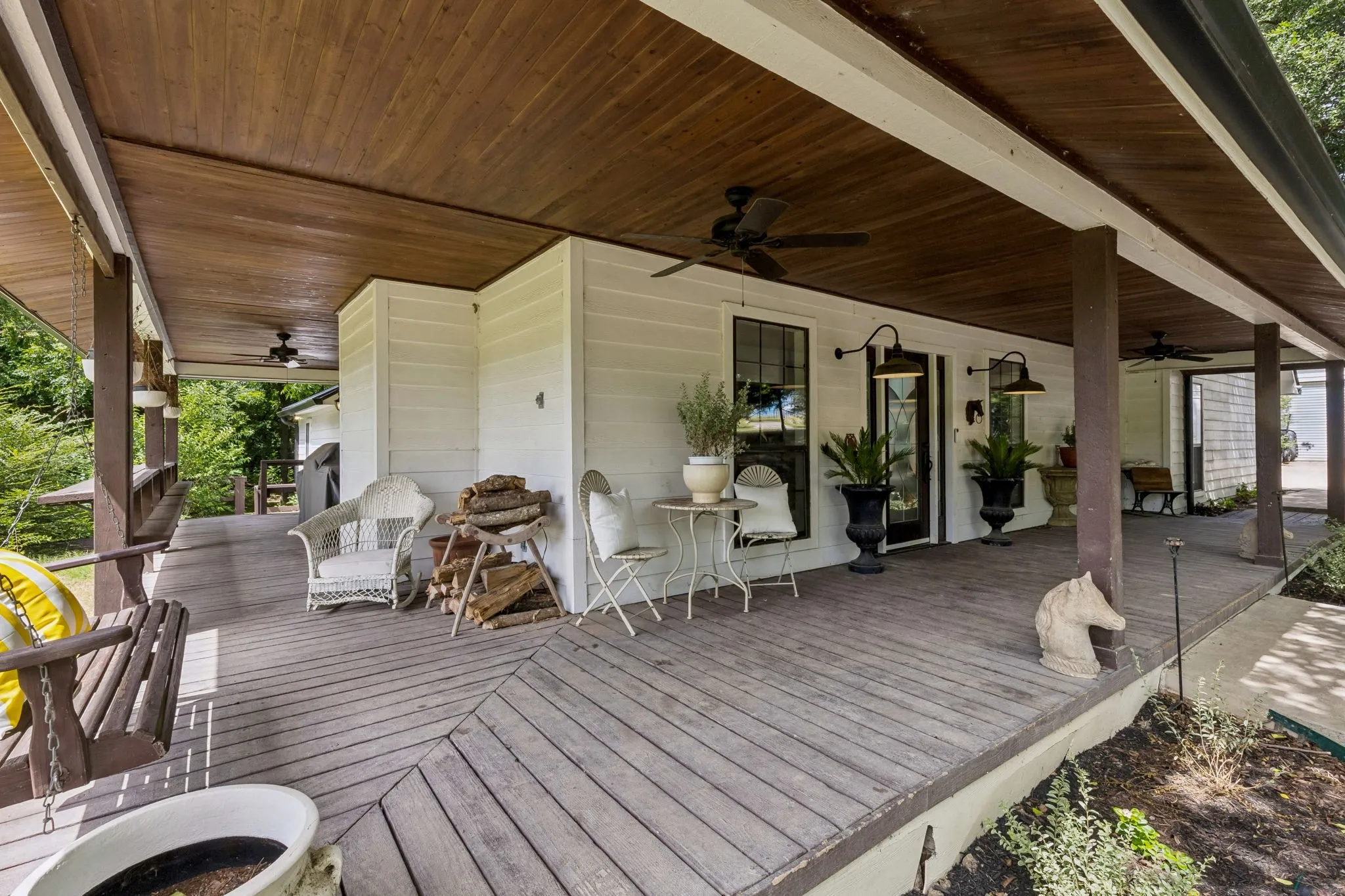 Spacious and inviting wraparound porch with wood ceiling.