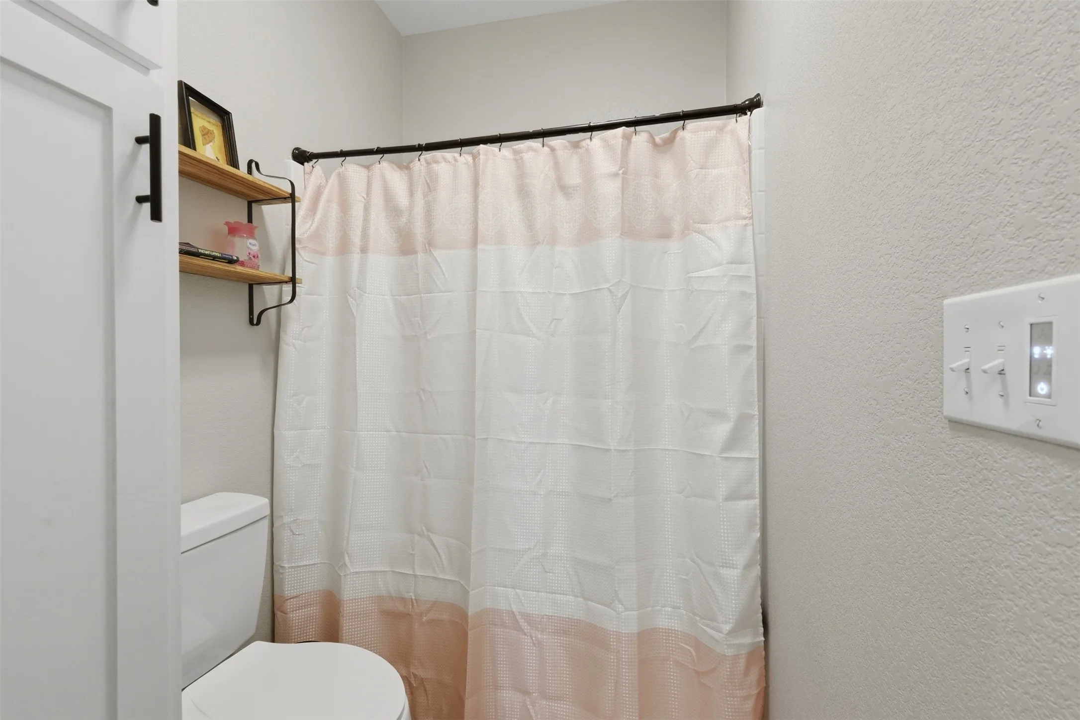 White interior door with black hardware, complementing the integrated two-tier wood shelving unit