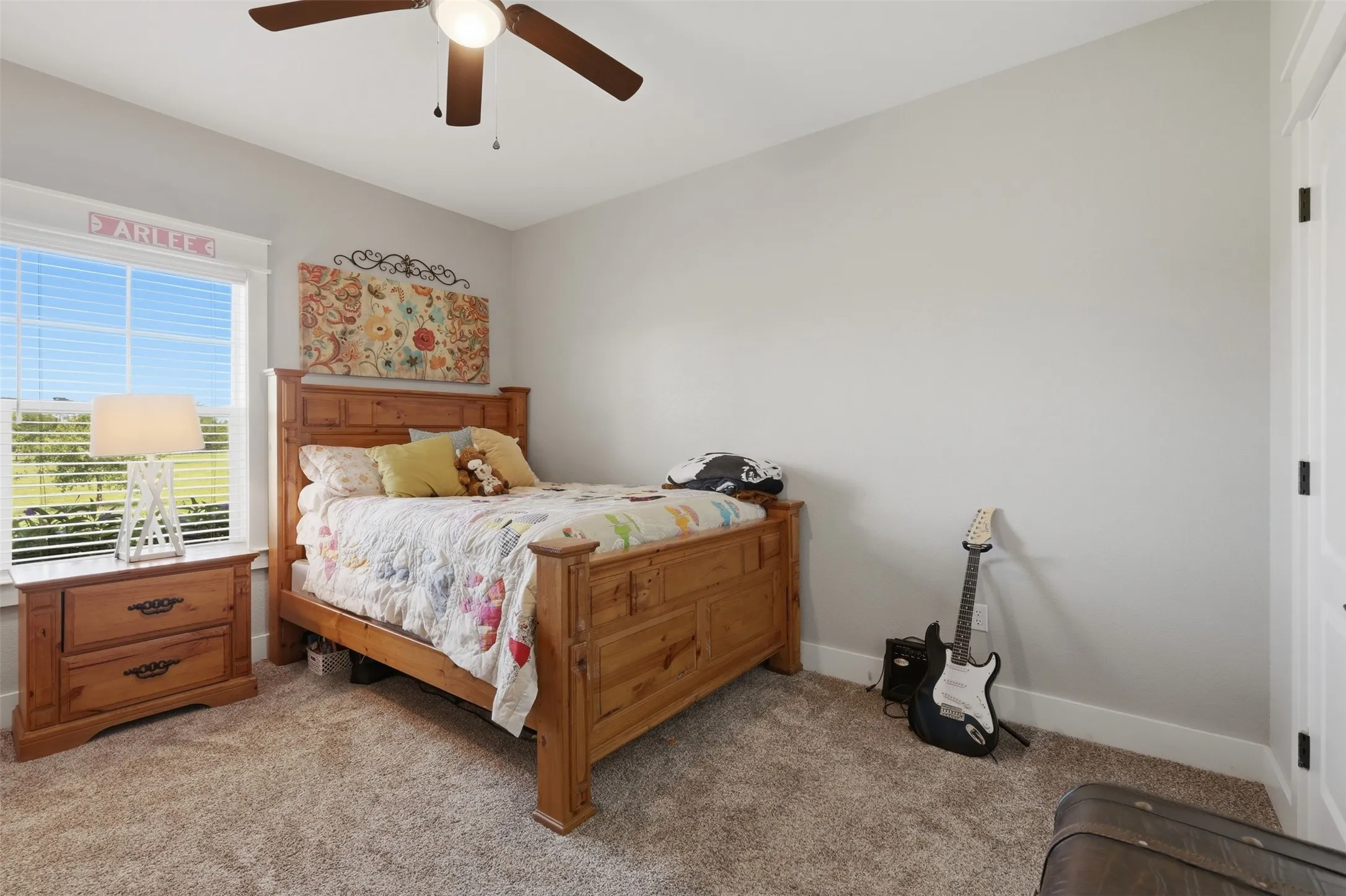 Carpeted room featuring a ceiling fan with integrated lighting, a window with horizontal blinds, and a white interior door
