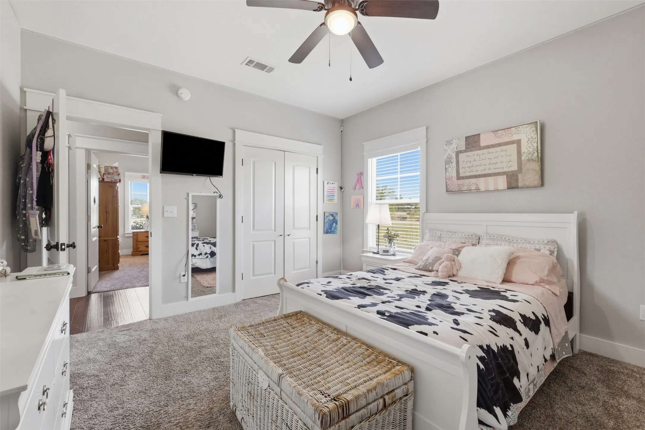 Carpeted bedroom featuring a ceiling fan, white trim, dual-panel closet doors, and a window with horizontal blinds