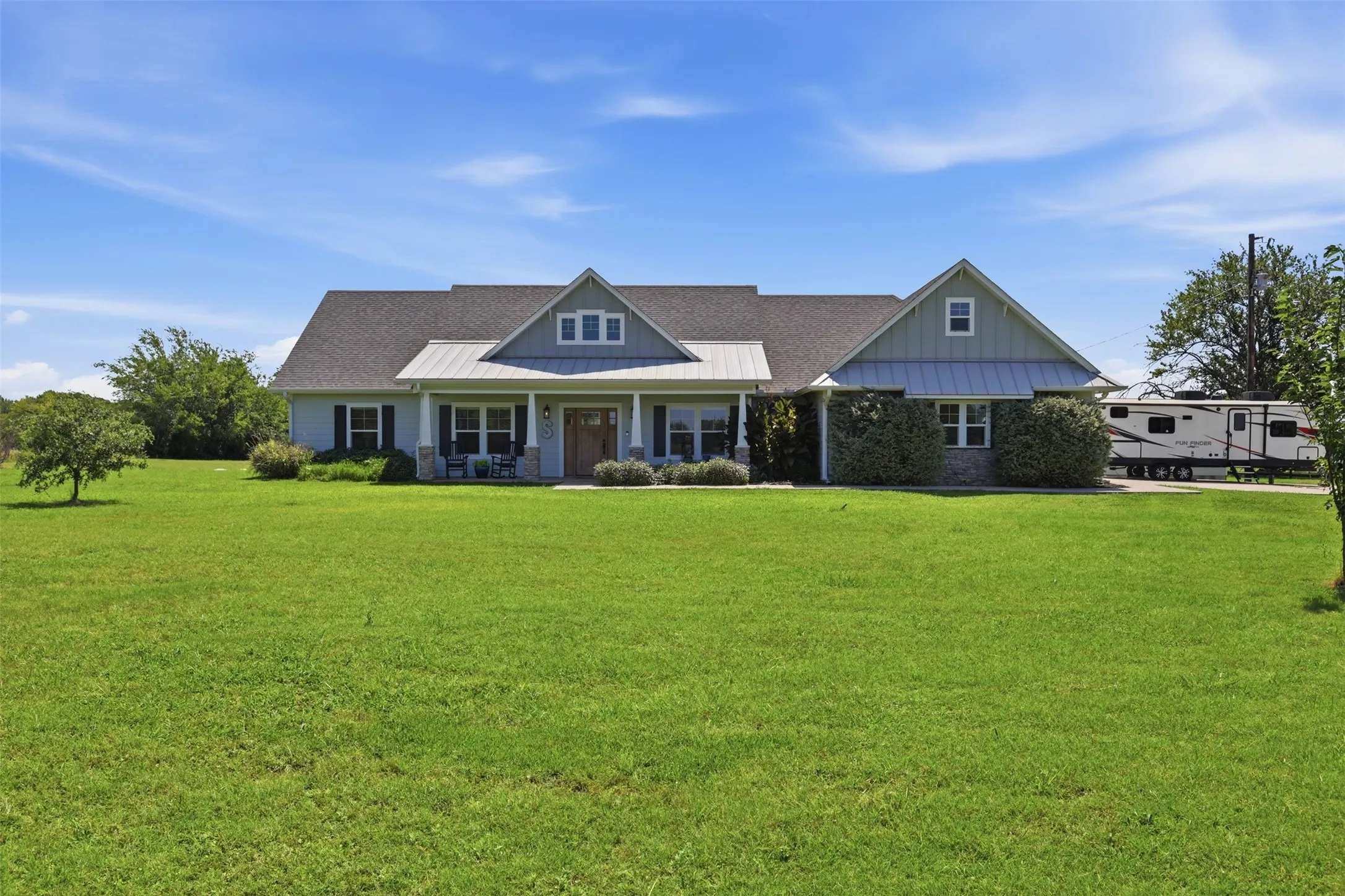 Expansive front lawn complementing a light blue siding exterior with stone accents and a covered front porch