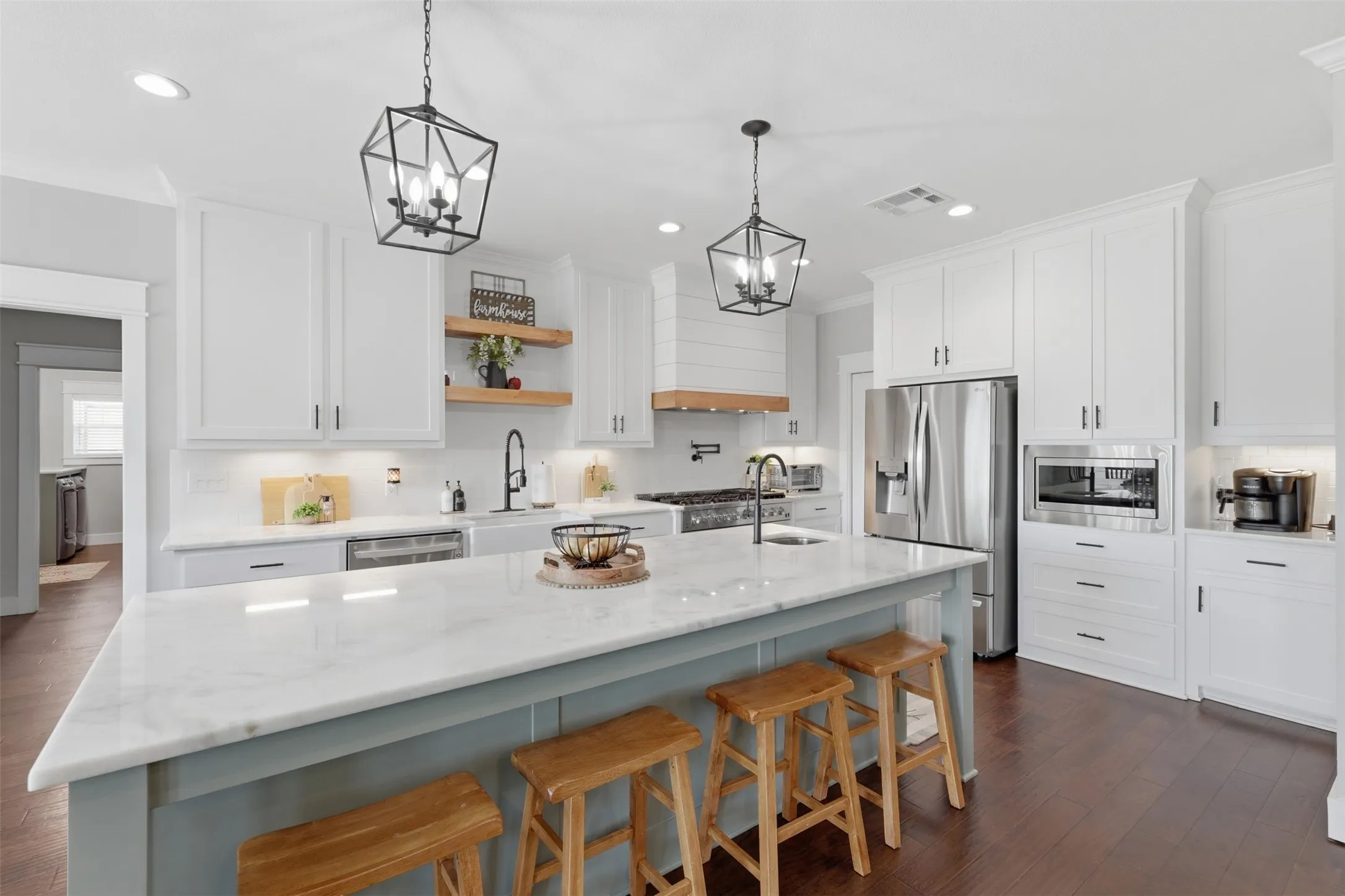 Kitchen featuring a large island with a stone countertop, white shaker cabinetry, stainless steel appliances, and dark wood-finish flooring