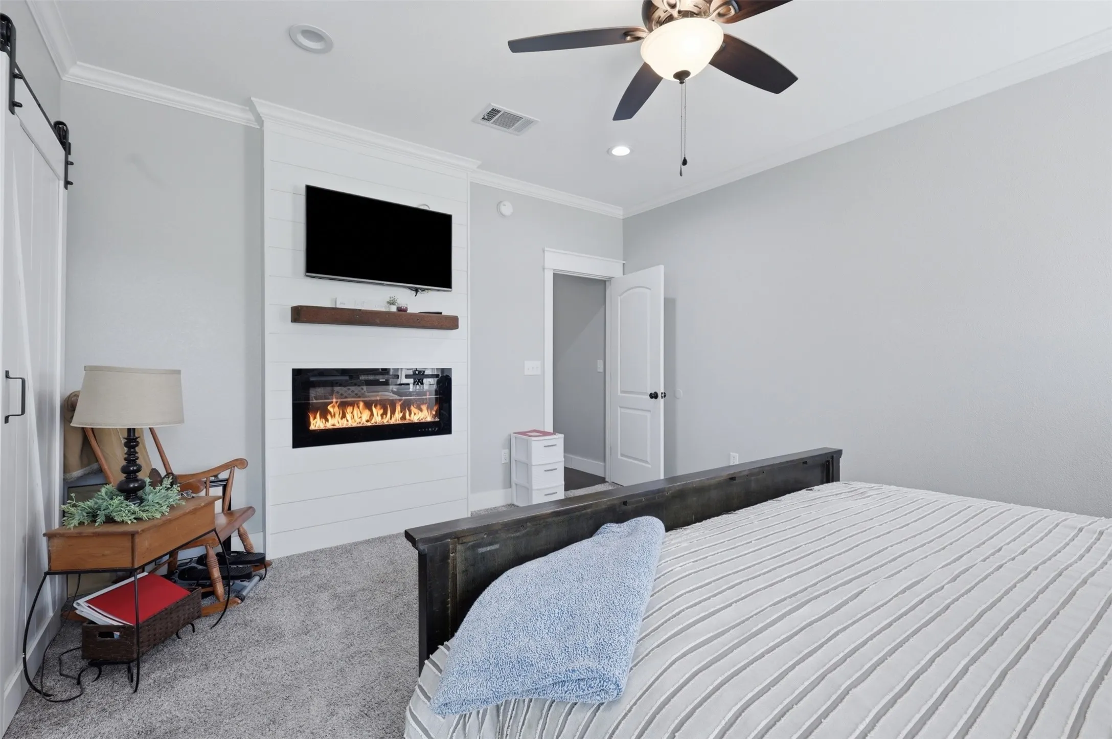 Integrated linear fireplace with shiplap-style surround, recessed lighting, crown molding, ceiling fan, and wood-finish flooring