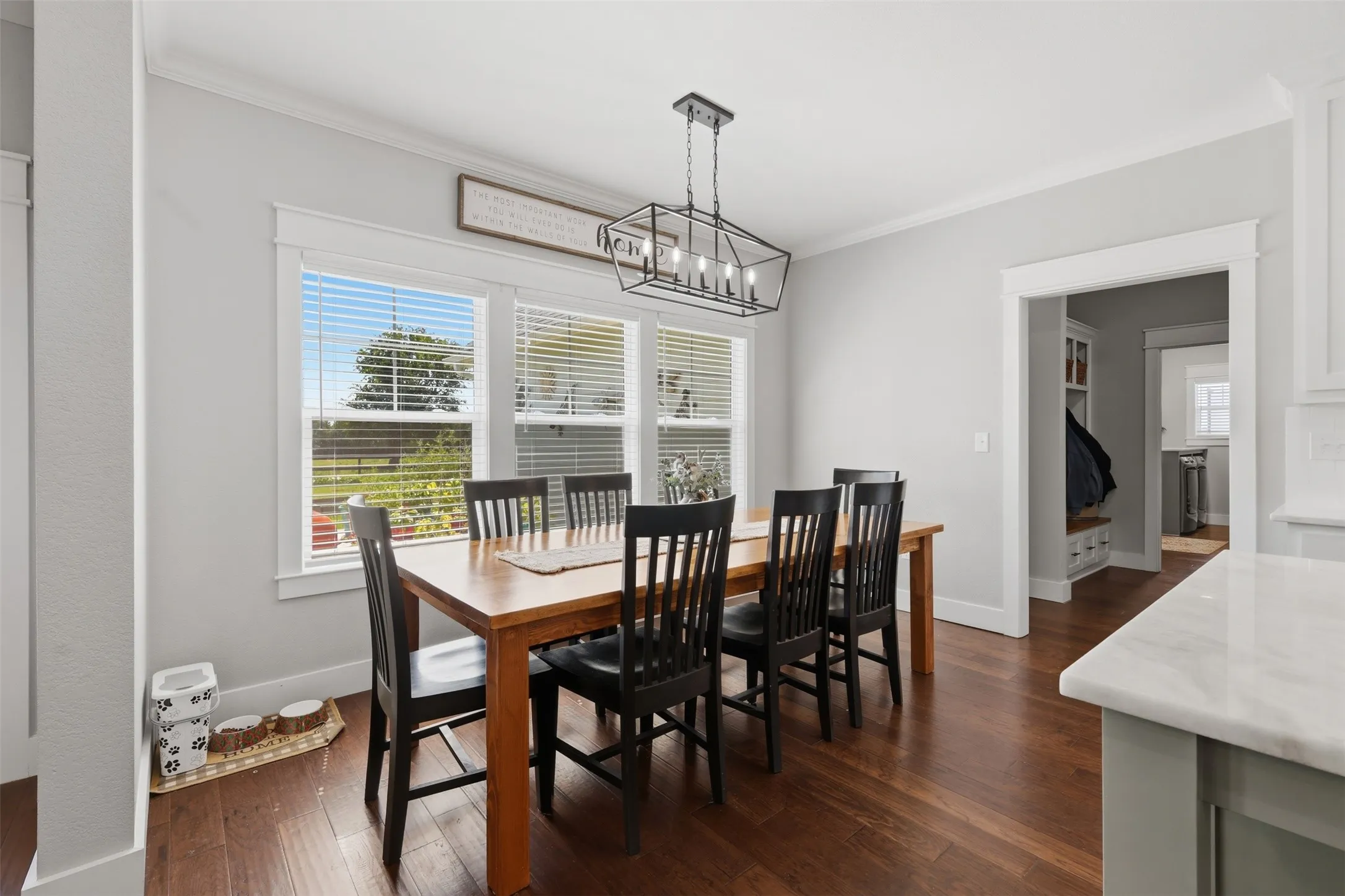 Dining area featuring a wood-finish floor, three windows with white blinds, and a black geometric chandelier