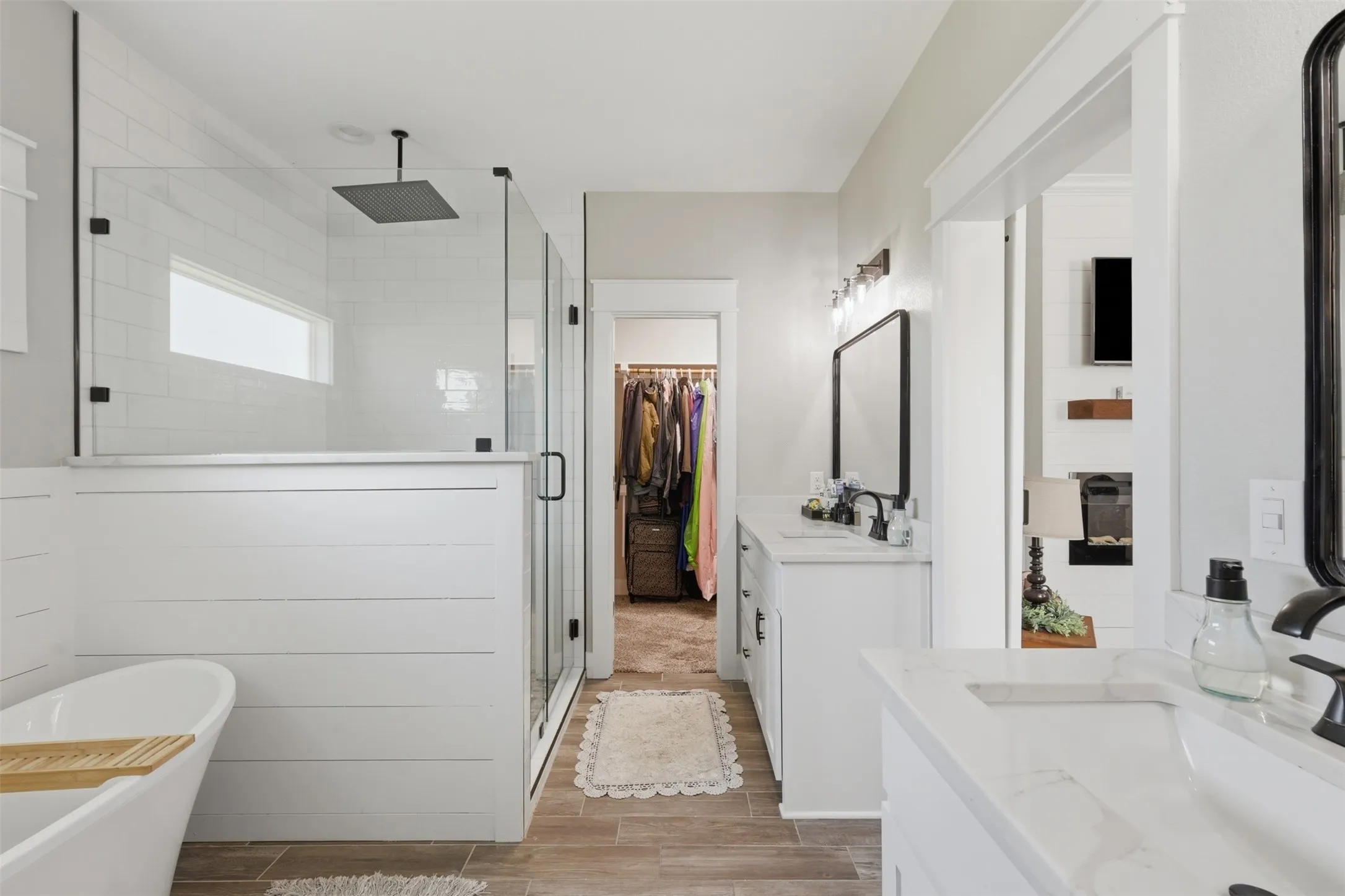 Spacious bathroom featuring a frameless glass shower enclosure with a rain showerhead, a freestanding soaking tub, and dual vanities with integrated sinks