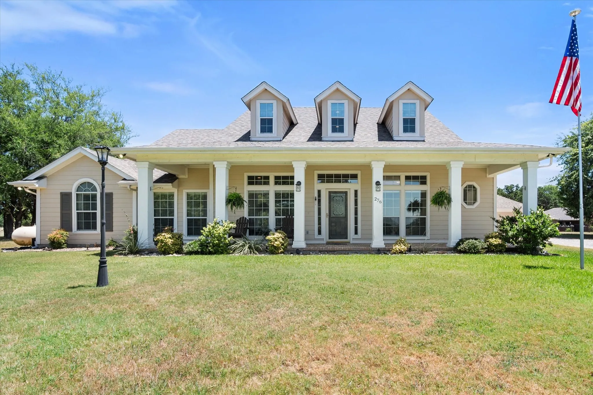 Daytime front exterior showcases the covered porch, dormer windows, and classic Southern Traditional architecture.