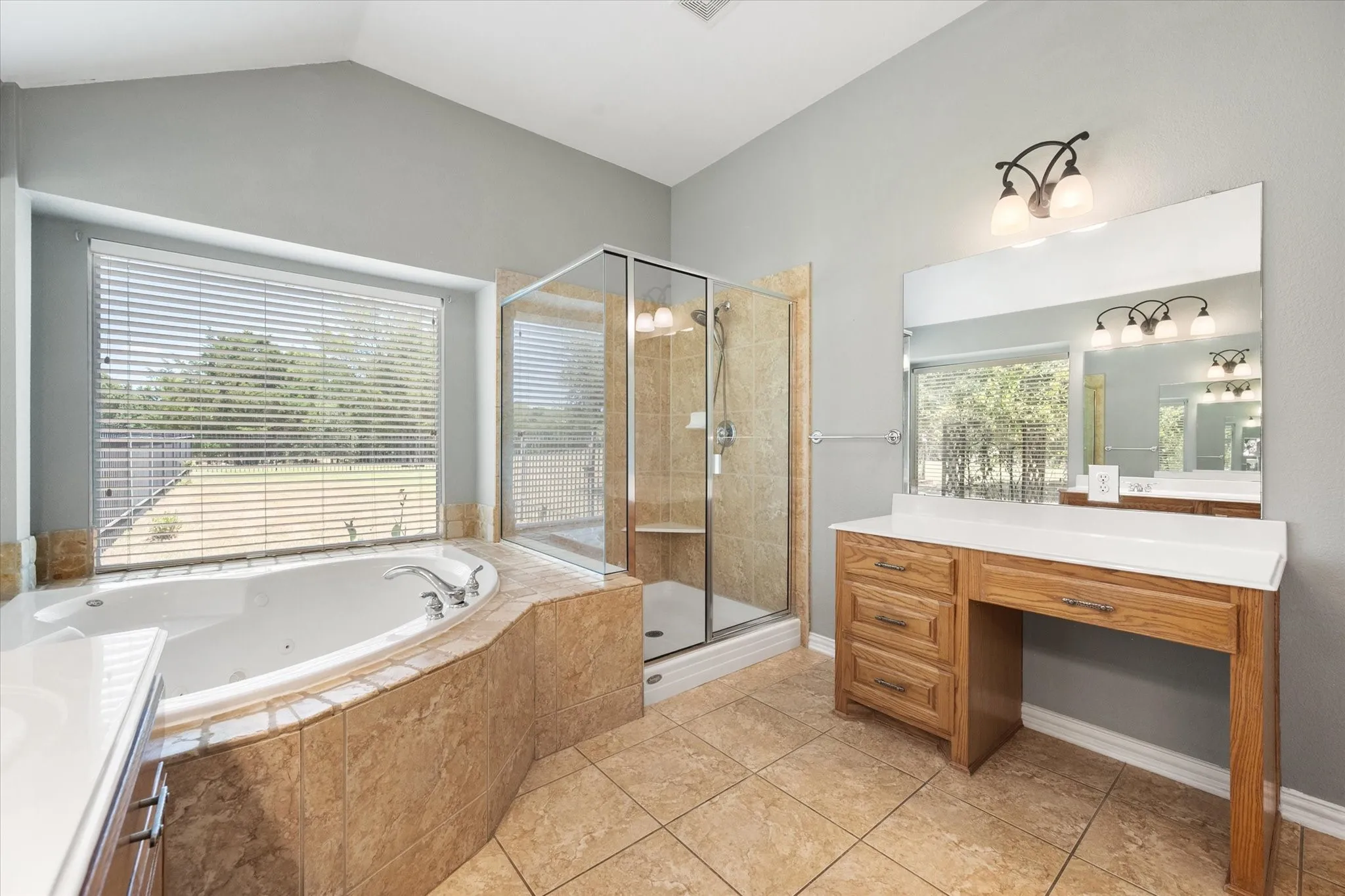 Primary bathroom includes a separate vanity, large mirror, garden tub, and glass-enclosed shower.