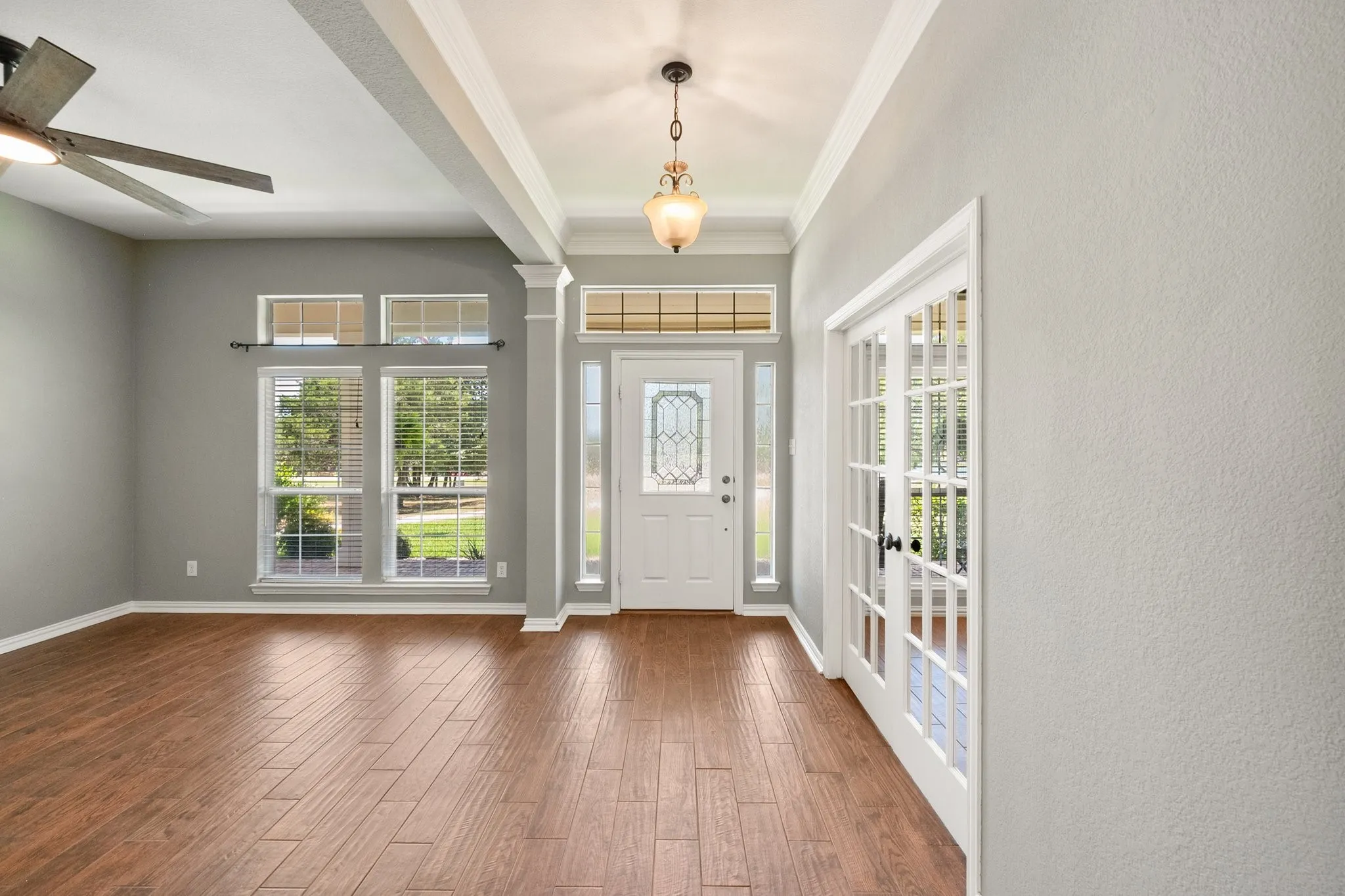 Bright entryway with French doors, tall windows, and warm wood flooring welcomes you into this Sweetwater Ranch home