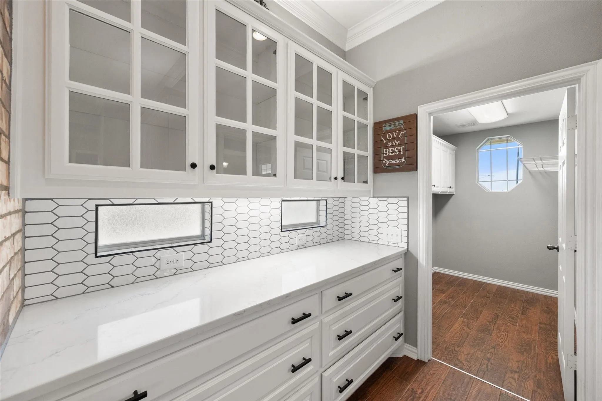 Butler’s pantry with glass-front cabinets and updated backsplash adds storage and style off the kitchen.