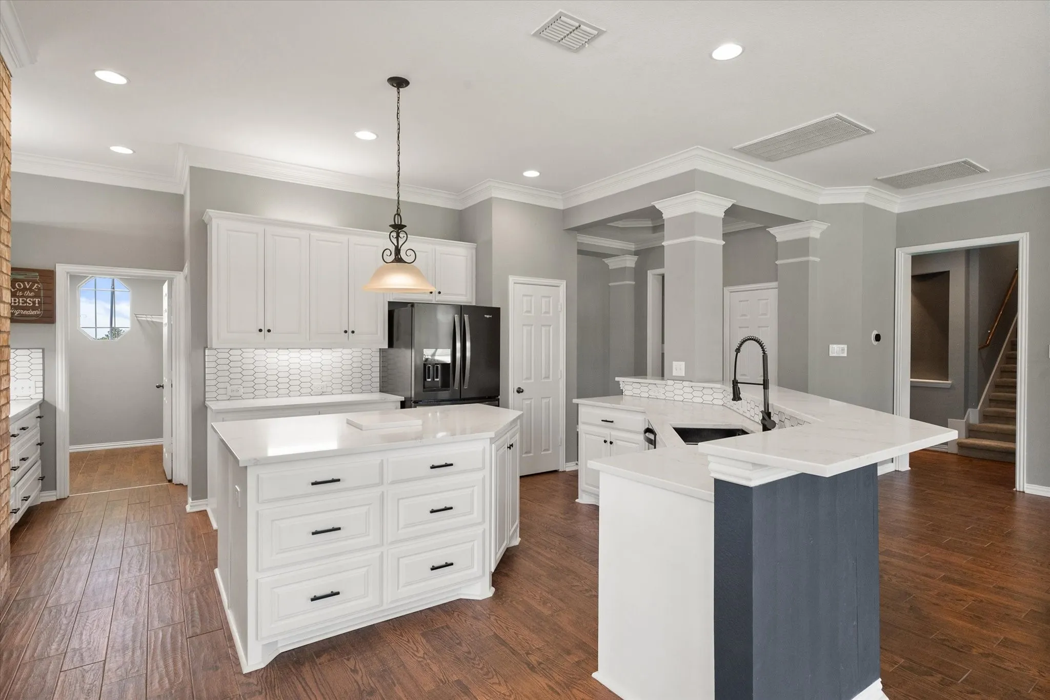 Updated kitchen features white cabinetry, granite counters, black fixtures, and a large island for gathering.