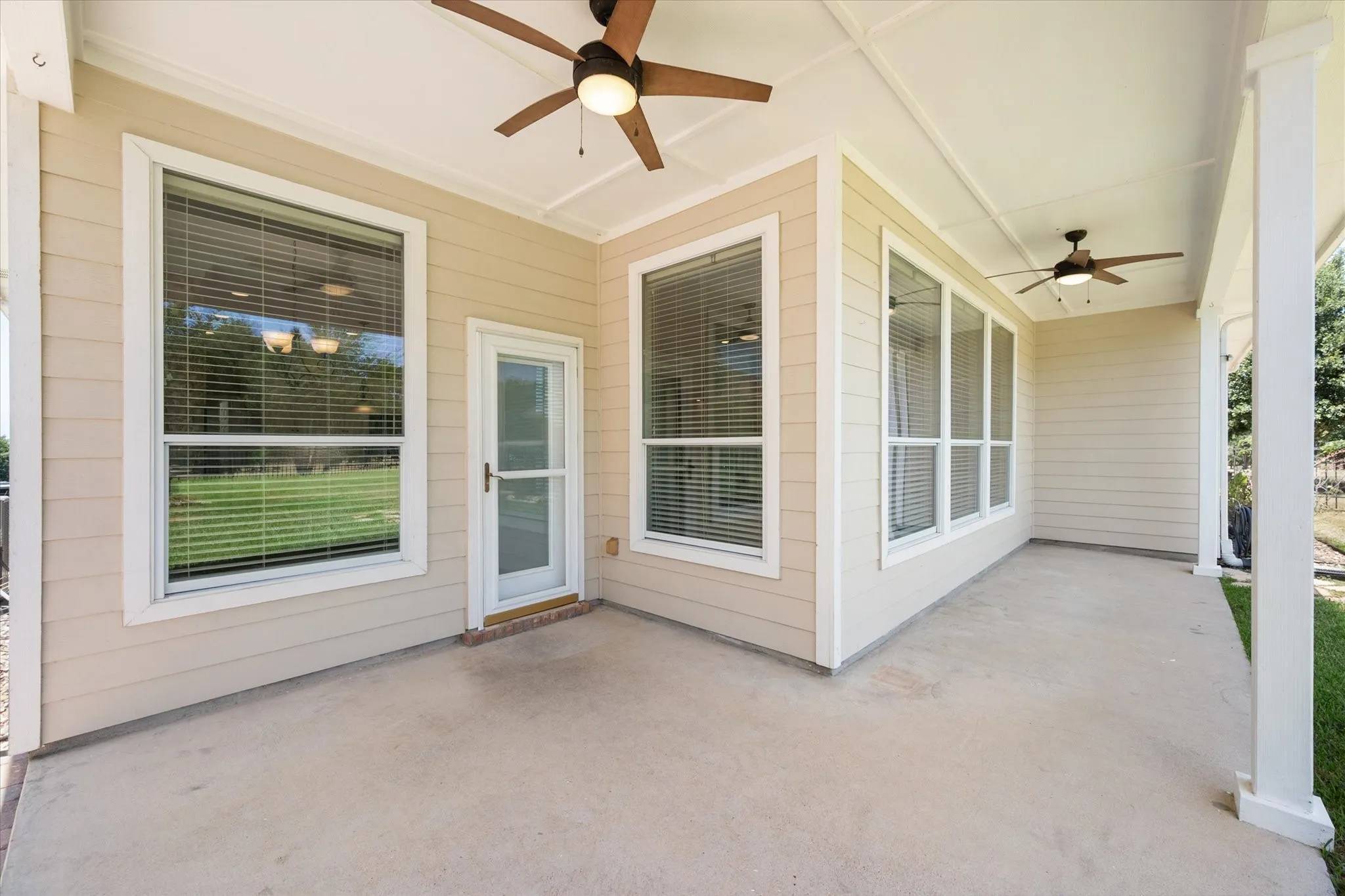 Covered back porch provides shaded outdoor living space overlooking the fenced backyard.