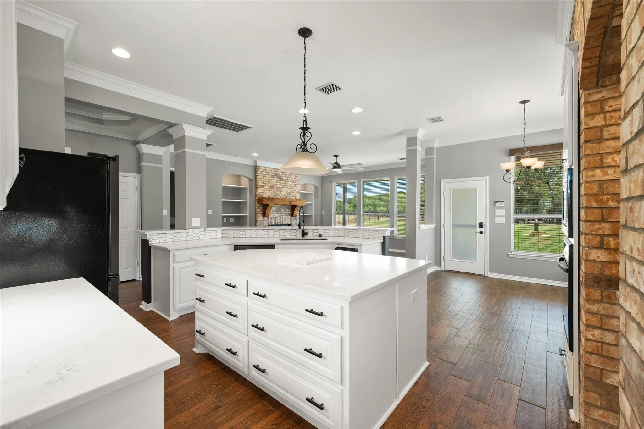 Kitchen island view shows open sightlines toward the breakfast room, living area, and backyard-facing windows.
