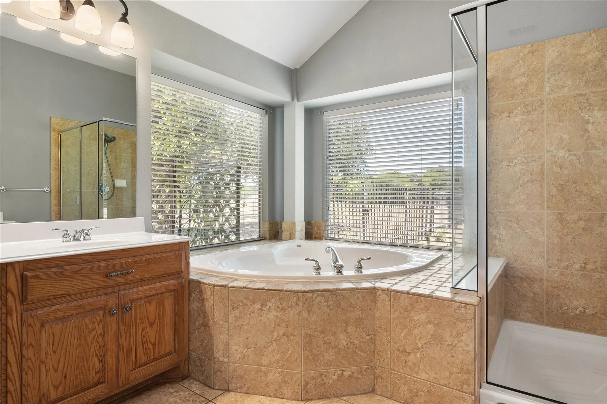 Garden tub and separate shower create a relaxing owner’s bath with natural light and backyard views.