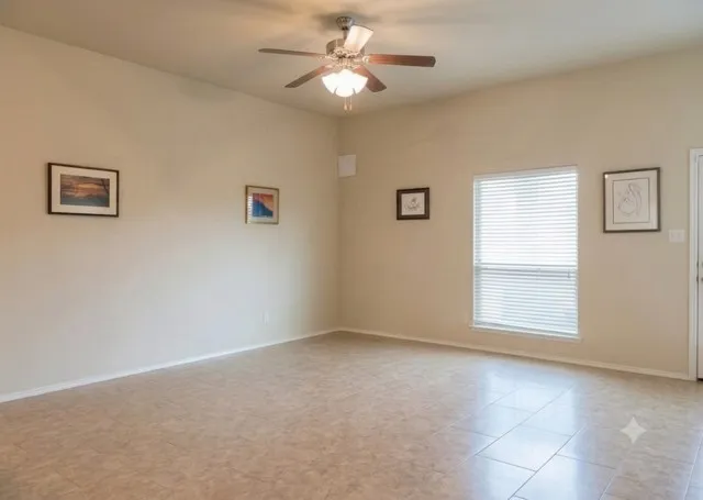 Spacious room featuring neutral tone walls, tile flooring, a window with horizontal blinds, and a ceiling fan with integrated lighting