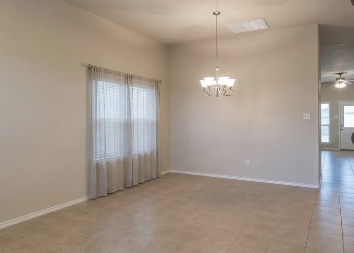 Spacious room featuring vaulted ceilings, neutral wall tones, and tiled flooring