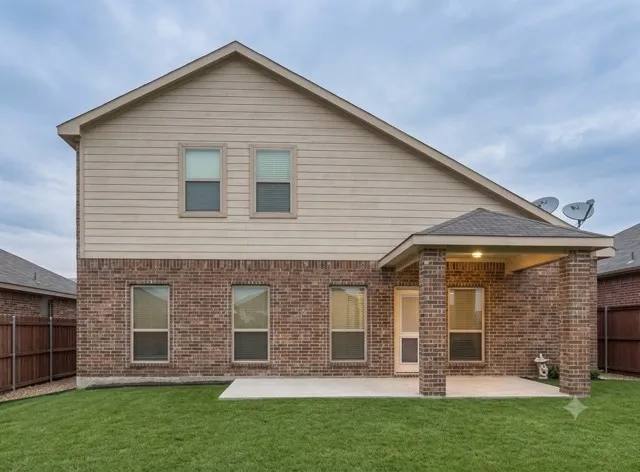 Brick and siding exterior featuring a covered patio and a manicured lawn