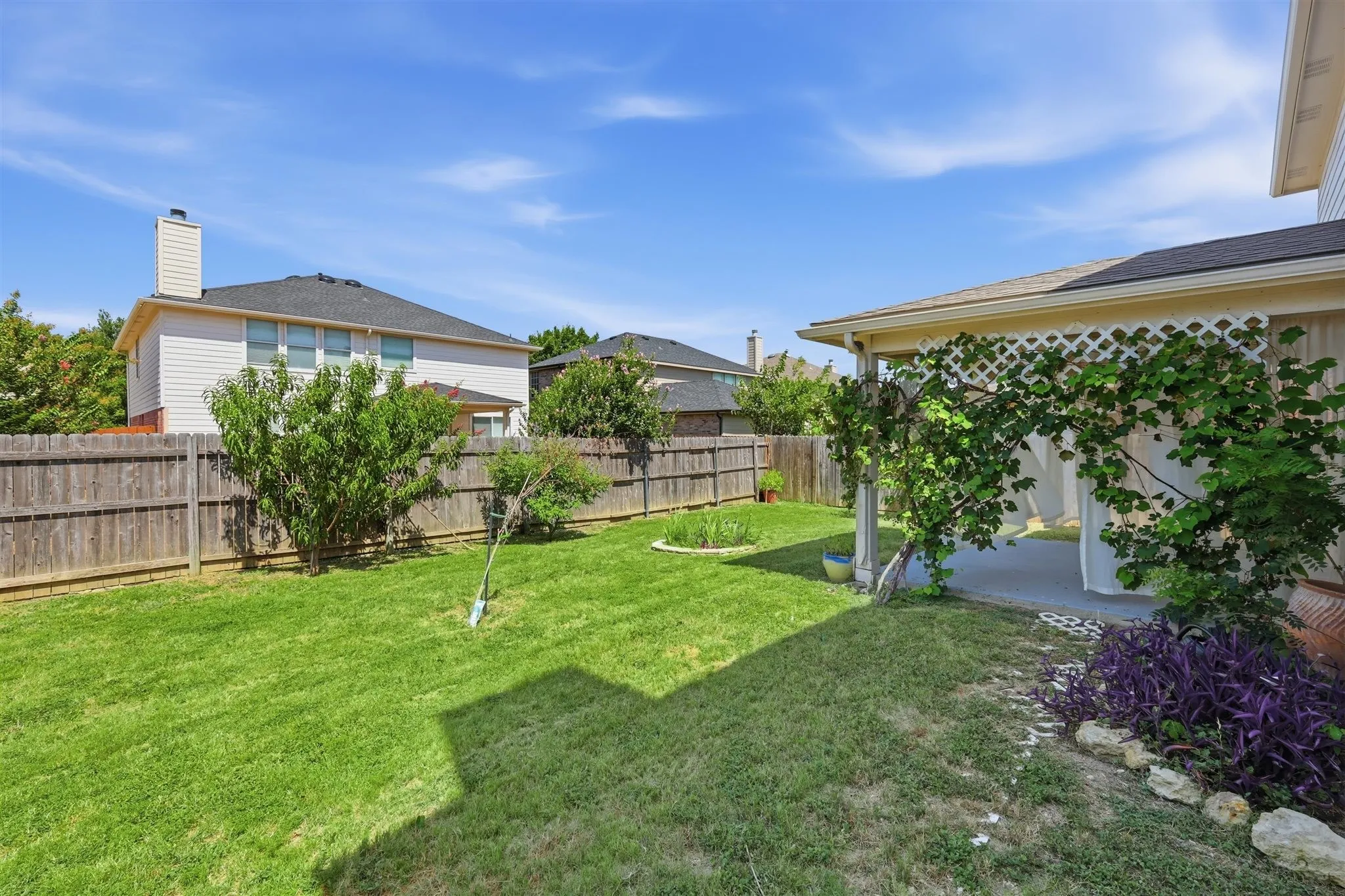 Expansive backyard featuring a manicured lawn, a full wooden privacy fence, and mature landscaping