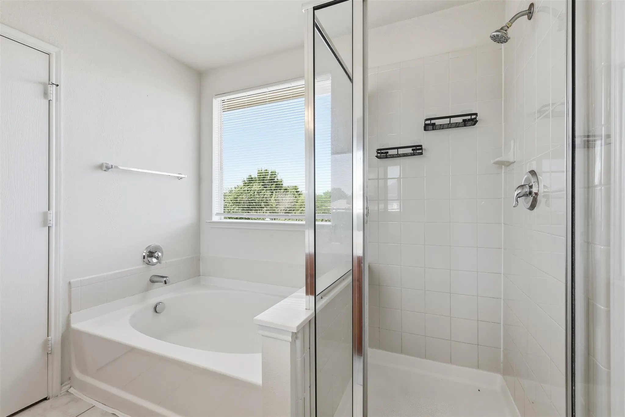 Bathroom featuring an enclosed shower with white tile surround, a built-in bathtub with chrome fixtures, and a window with blinds