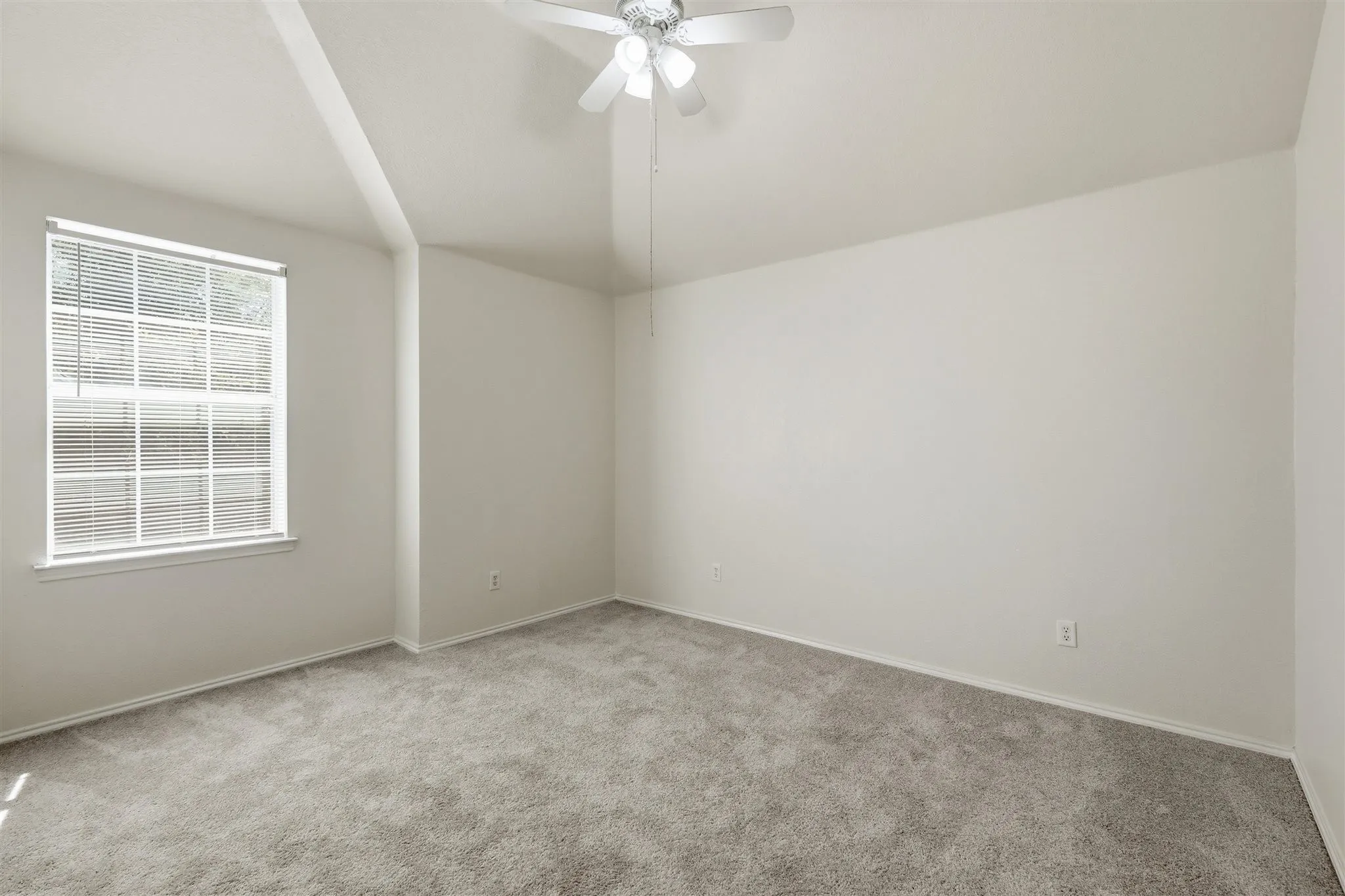 Spacious room with vaulted ceilings, neutral-toned walls, and plush carpeting