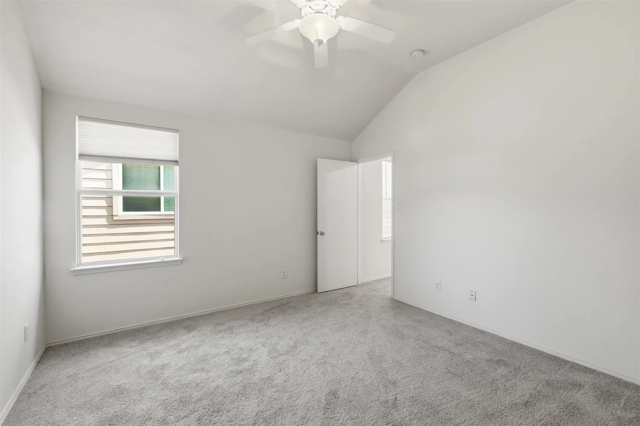 Carpeted room featuring a vaulted ceiling and a ceiling fan