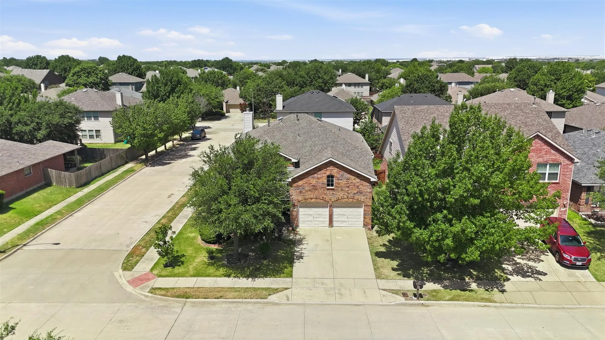 Traditional brick exterior with an attached two-car garage, concrete driveway, and mature landscaping
