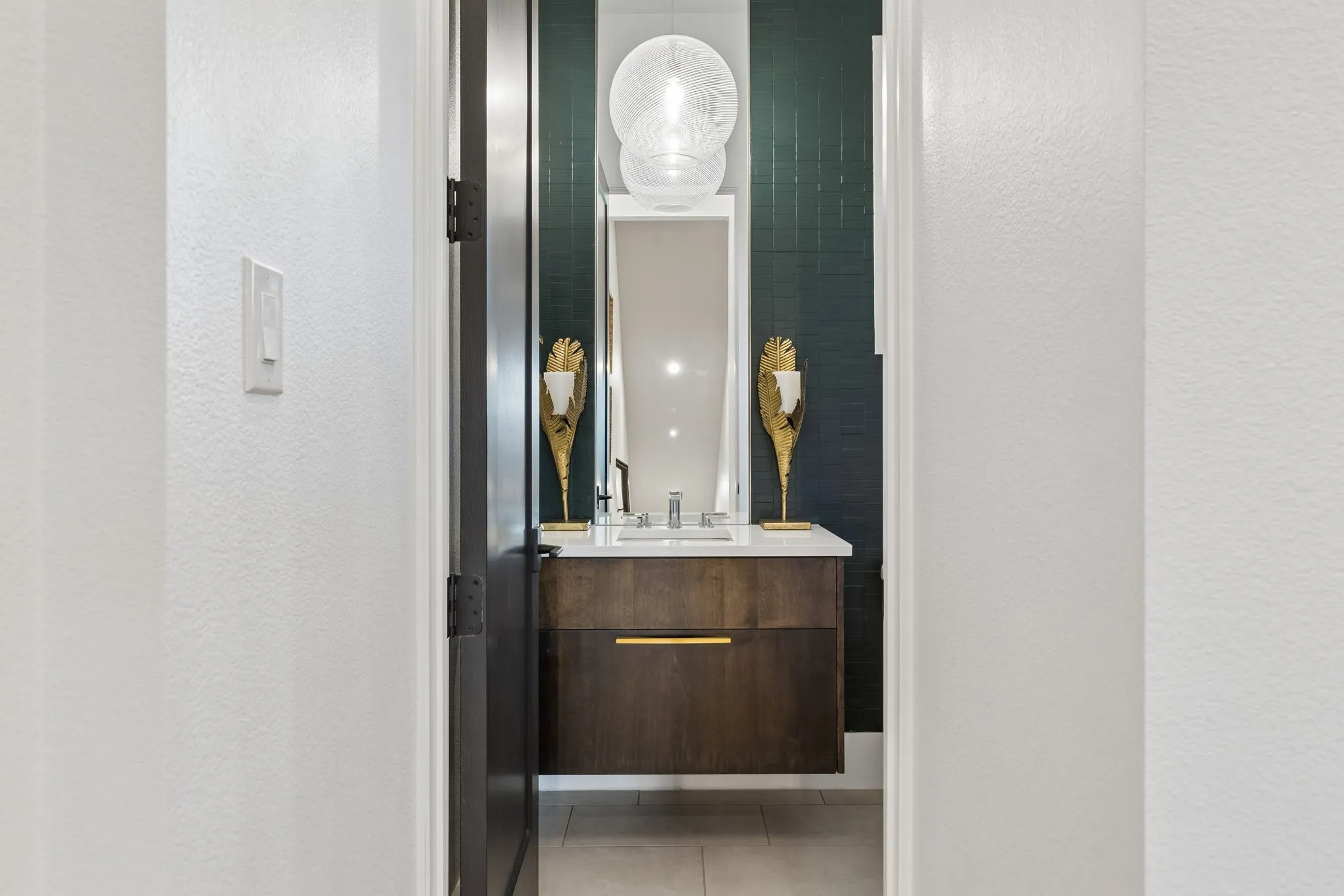 Main level Powder Bath with luxury lighting gold hardware and dark wood cabinetry