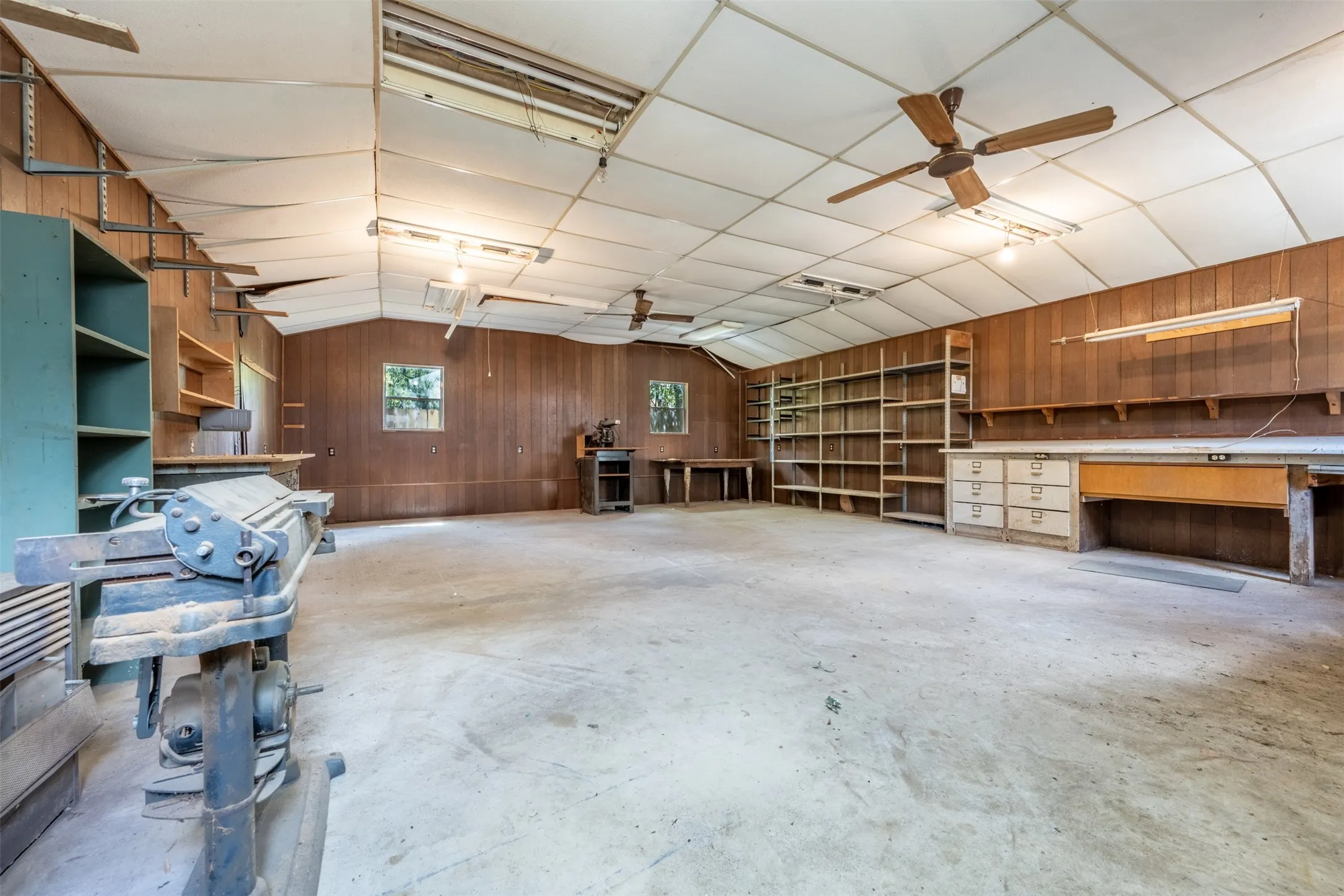 Expansive concrete flooring with wood-paneled walls and ceiling fans