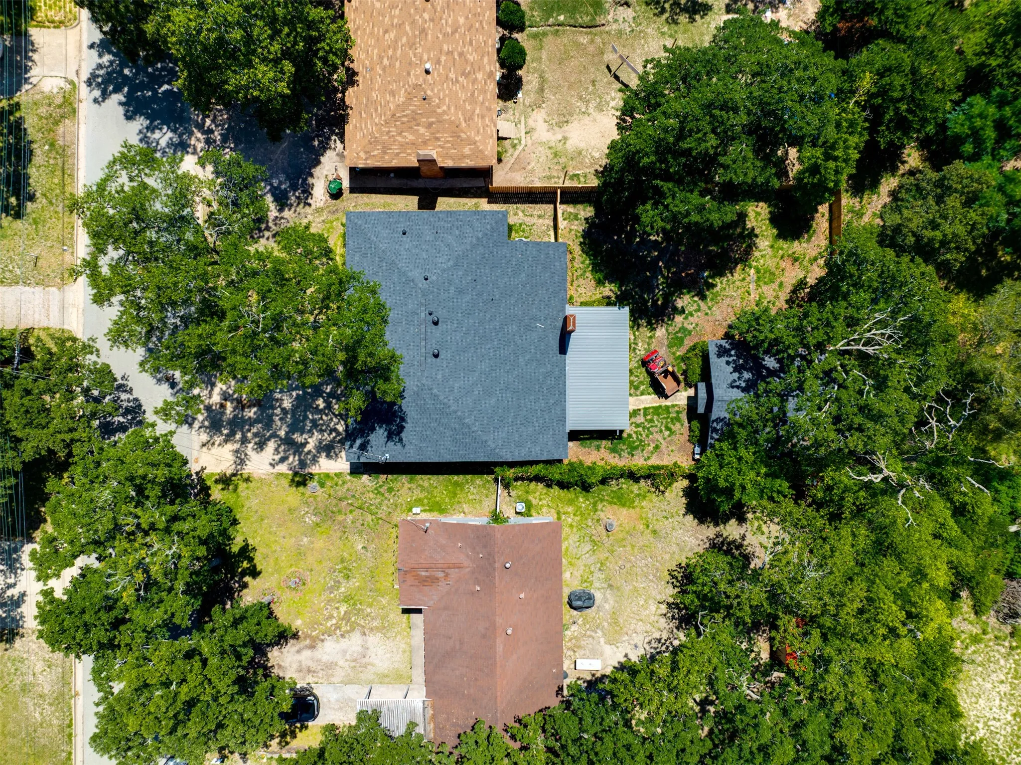 Aerial view of House & Workshop  showcasing a property with a dark shingle roof, mature trees, and a detached structure