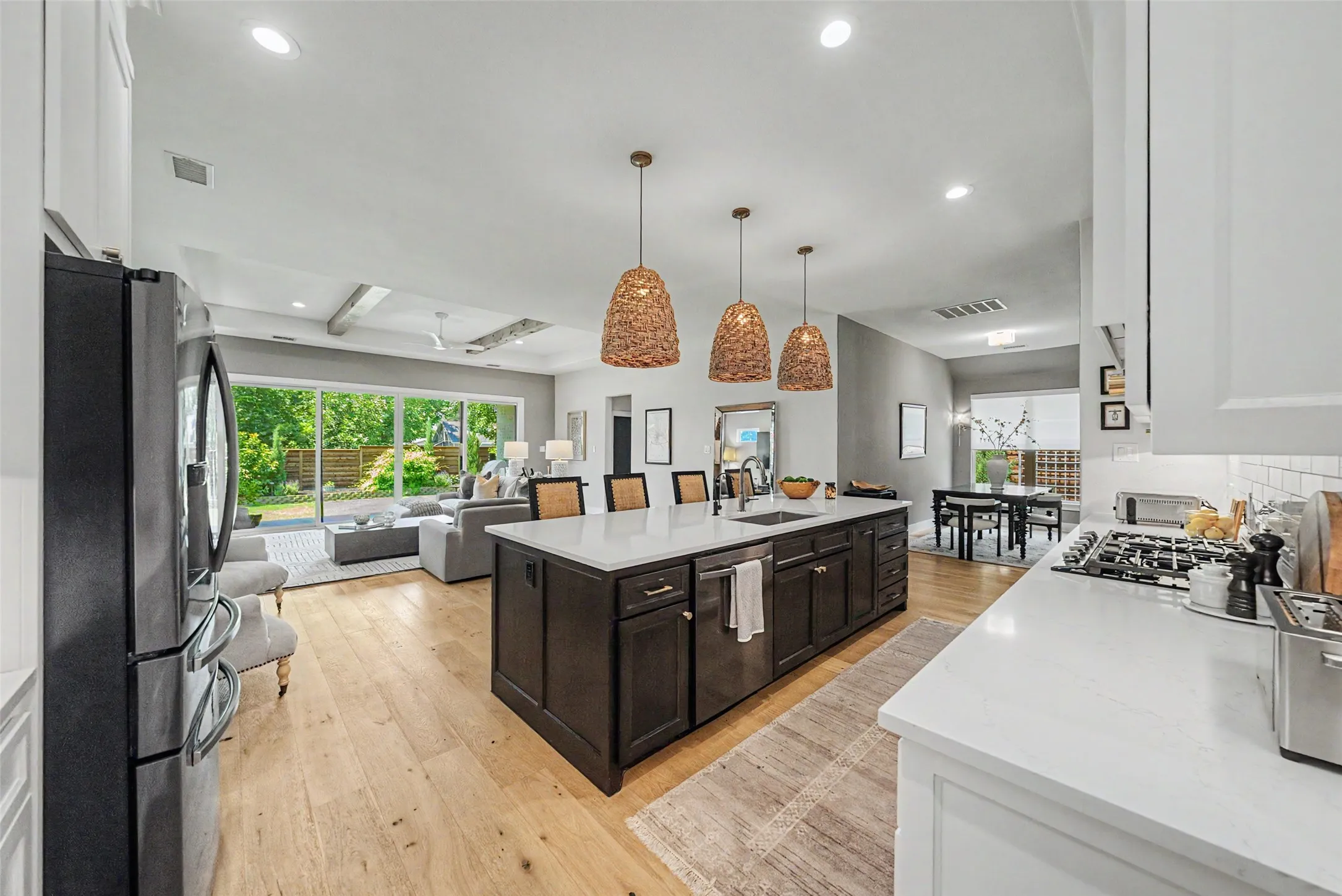 Open-concept kitchen featuring an oversized island with seating, a gas range with subway tile backsplash, recessed lighting, and wood-finish flooring throughout