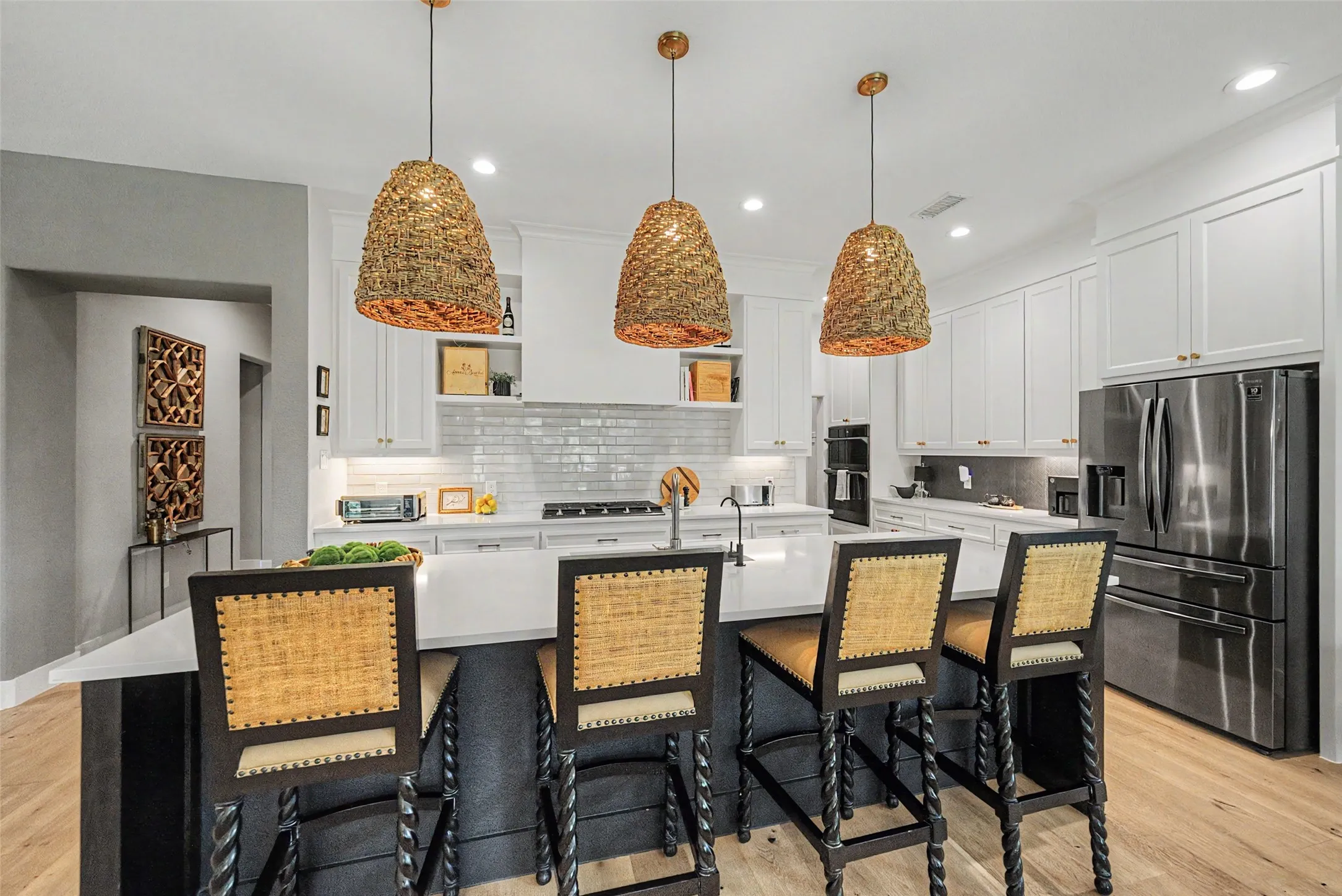 Kitchen featuring a large island with seating, pendant lighting, white shaker cabinetry, stainless steel appliances, and wood-finish flooring